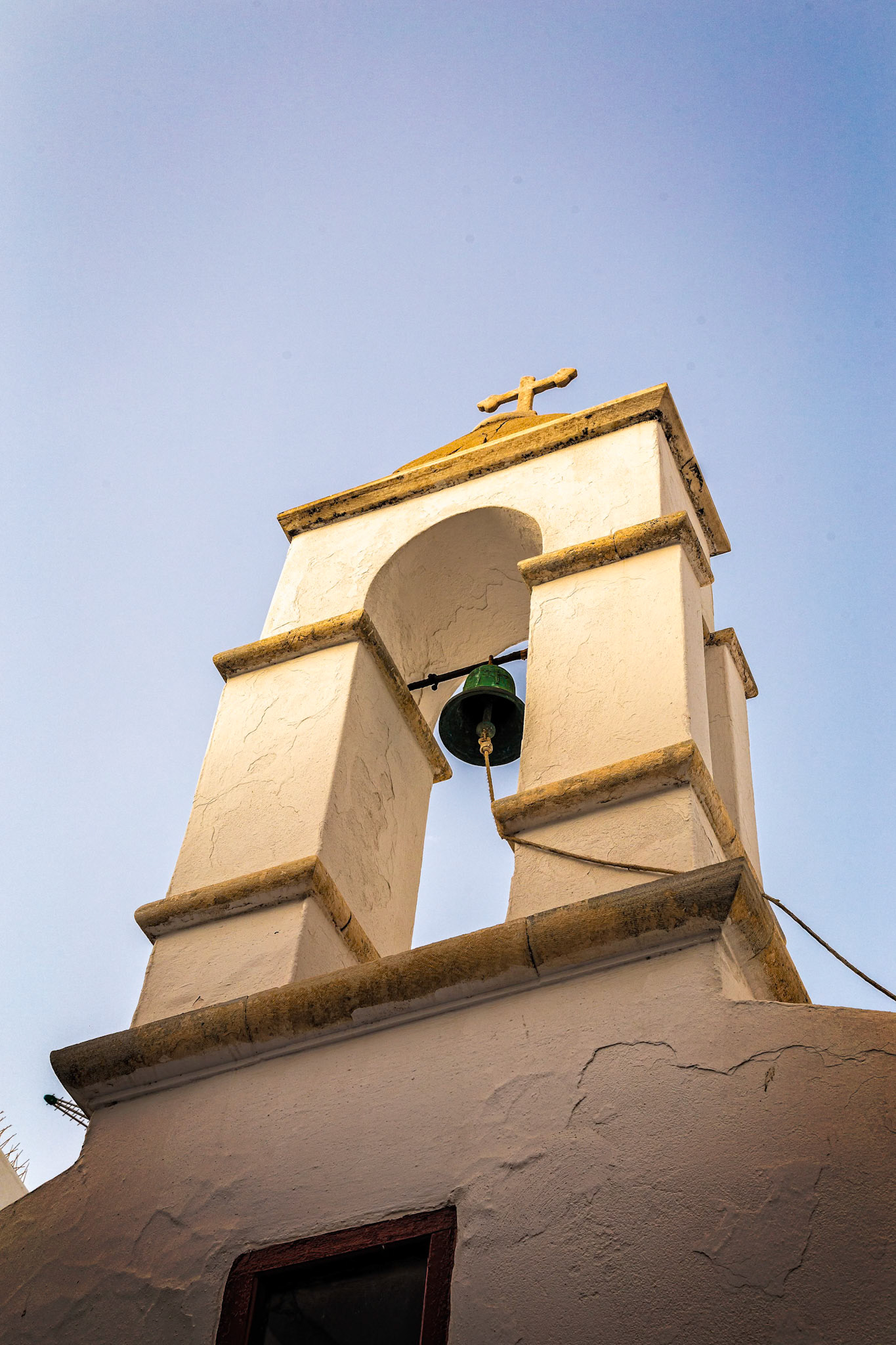 Mykonos, Greece - May 23rd 2018: A whitewashed church bell tower stands against the blue sky, a symbol of faith and tradition.