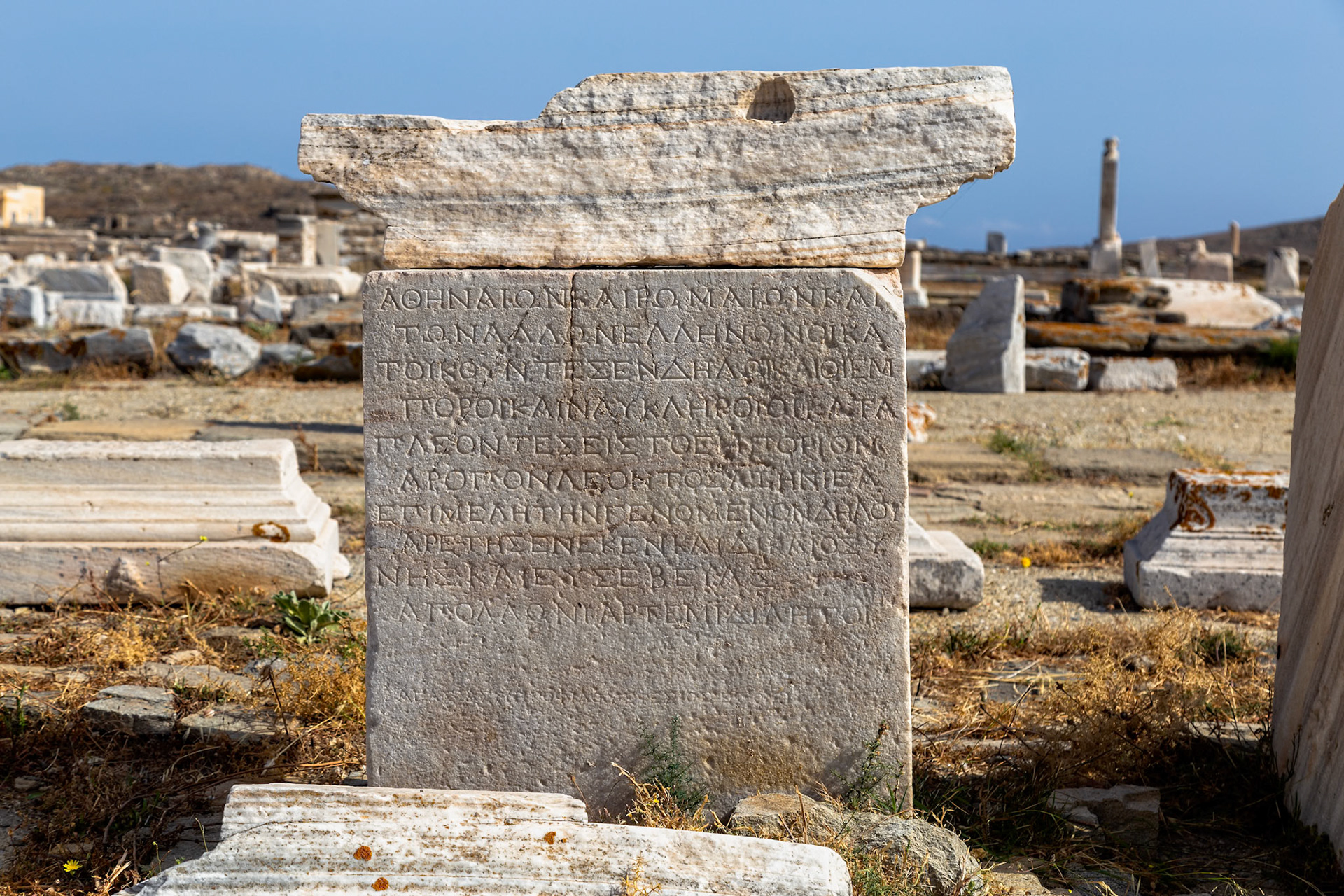 Delos, Greece - May 22nd 2018: An ancient stone tablet with Greek inscriptions stands among ruins, preserving history and culture for future generations.
