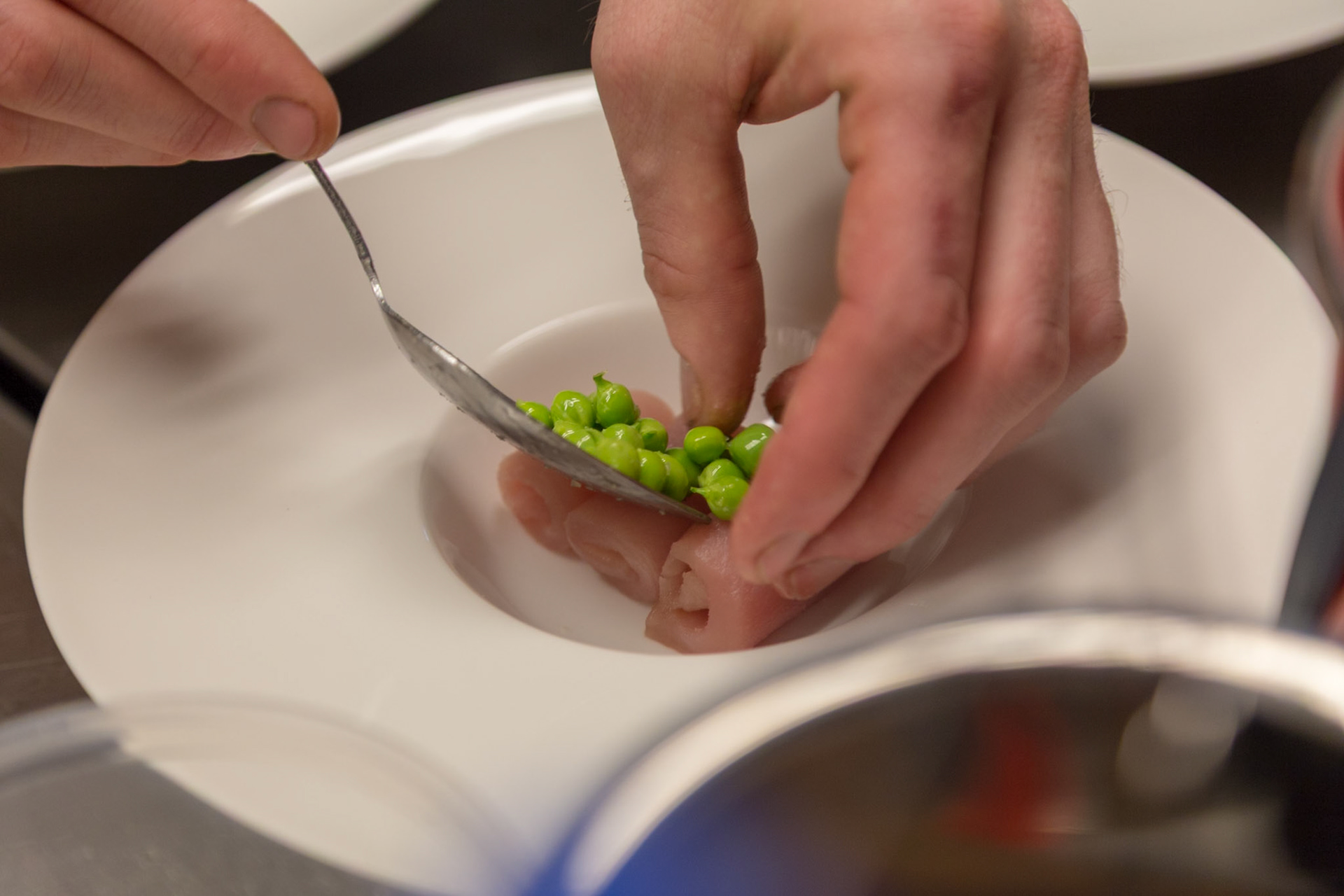 Fog Lark, Portland, Oregon - April 6th 2018: A chef plates a dish with tuna and peas, adding the final touches for presentation.