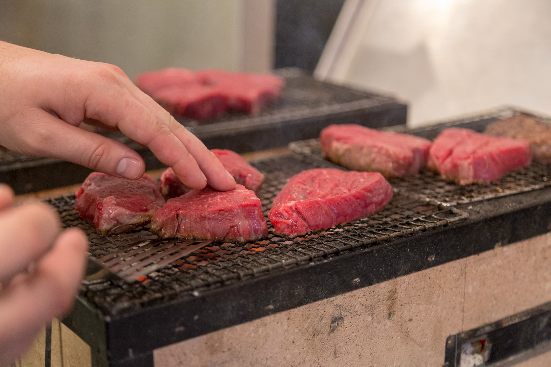 Fog Lark, Portland, Oregon - April 6th 2018: A chef is grilling raw beef on a grill, cooking it to perfection for a delicious meal.