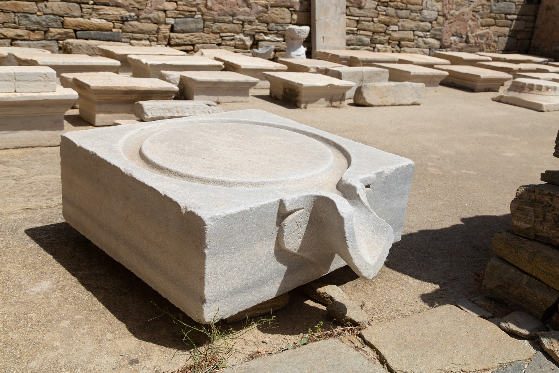 Delos, Greece - May 22nd 2018: An ancient marble offering table sits among other ruins. These tables were used for libations and sacrifices to the gods.