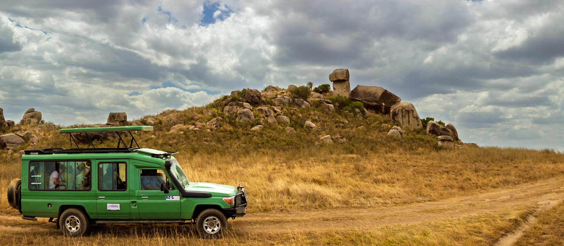Tourists in a safari vehicle explore the Serengeti National Park in Tanzania, seeking wildlife amidst the iconic landscape.