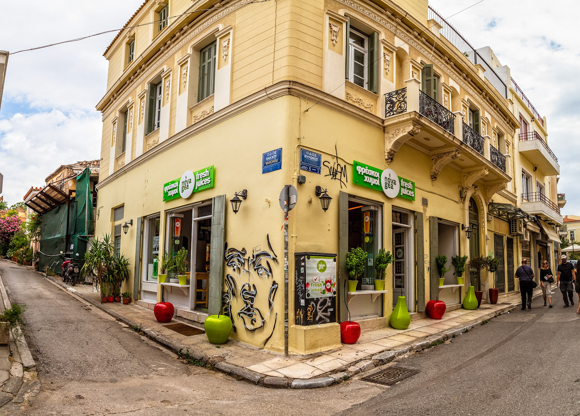 Athens, Greece - May 23rd 2018: A Nova Gea fresh juice shop sits on the corner of a street, with people walking by, offering healthy drinks to passersby.