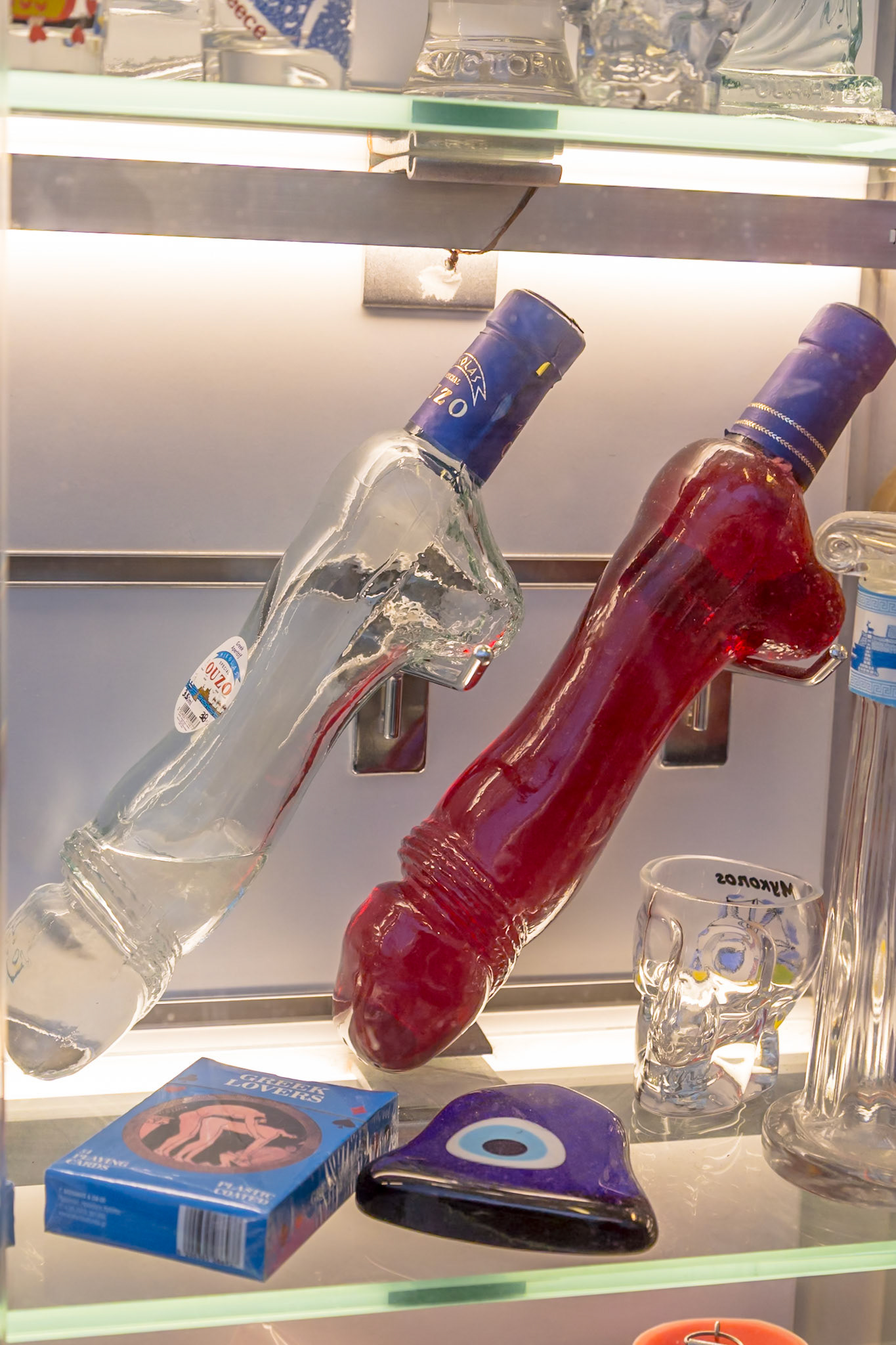 Mykonos, Greece - May 23rd 2018: Novelty Ouzo bottles and Greek Lover playing cards are displayed for sale in a shop window.