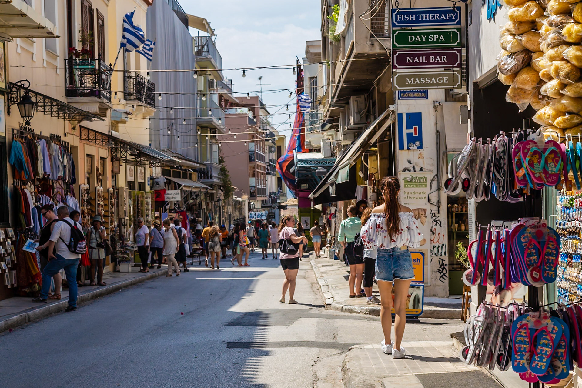 Athens, Greece - May 23rd 2018: Tourists stroll along a bustling street lined with shops and restaurants, enjoying the vibrant atmosphere of the city.