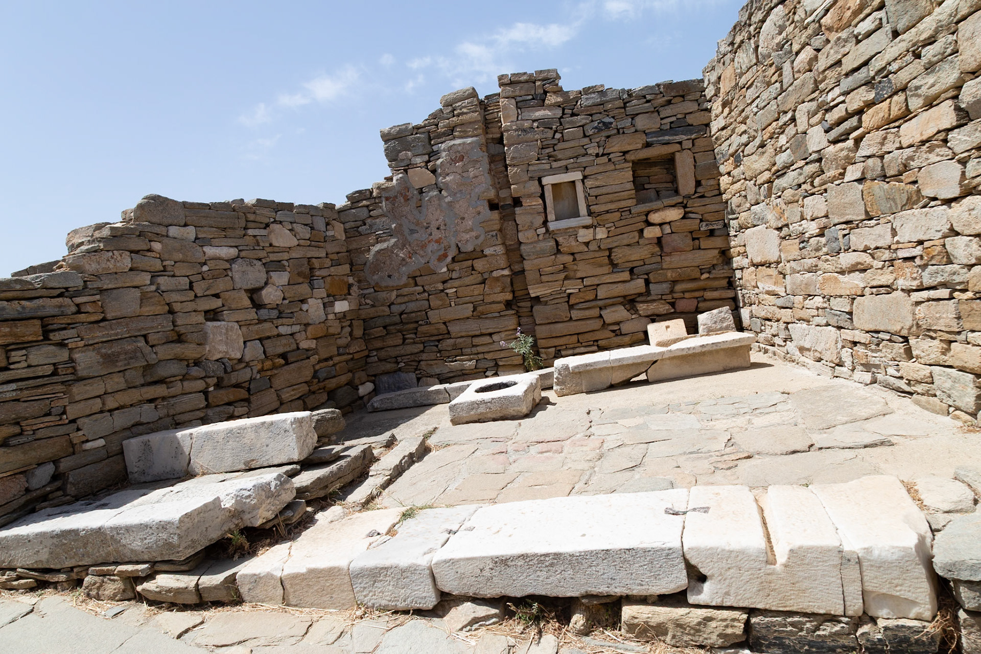 Delos, Greece - May 22nd 2018: An interior view of a stone structure, possibly a temple or house, showcasing ancient architecture and design.