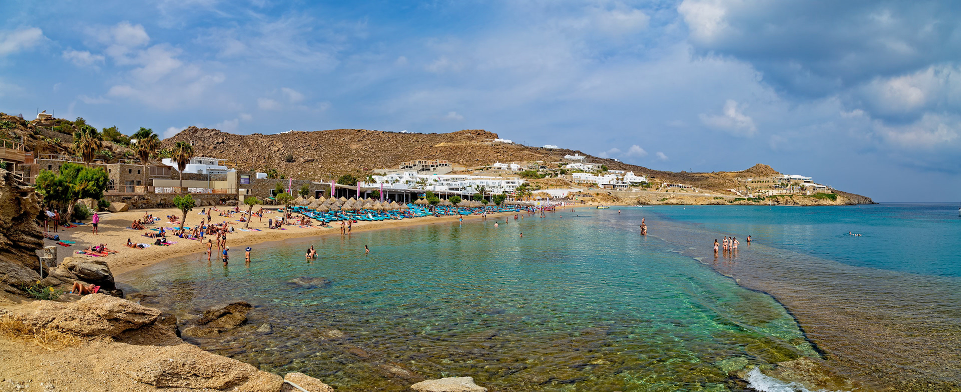 Paradise Beach, Mykonos, Greece - May 24th 2018: People enjoy swimming and sunbathing at the popular Paradise Beach, known for its lively atmosphere.