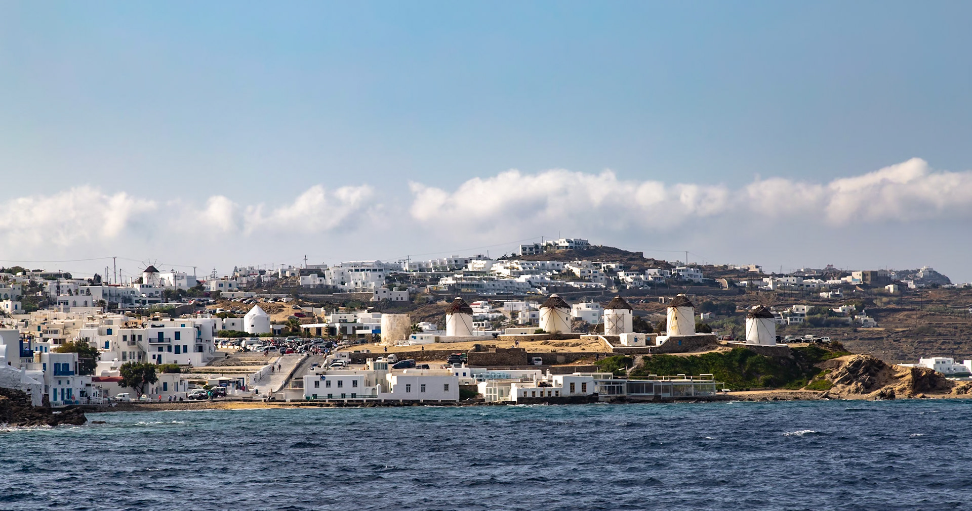 Mykonos, Greece - May 23rd 2018: A scenic view of the iconic windmills and whitewashed buildings of Mykonos, a popular tourist destination.