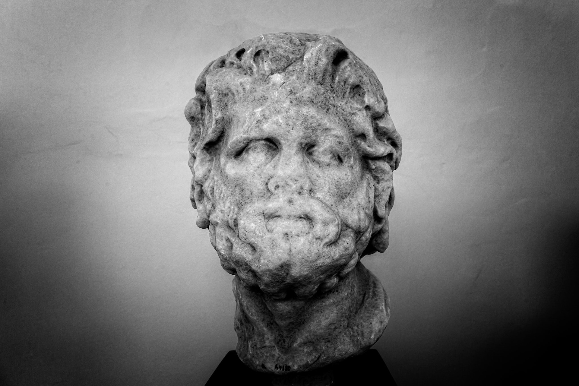 Delos, Greece - May 22nd 2018: A weathered marble head of a man, possibly a deity or important figure, is displayed, showcasing ancient Greek sculpture and artistry.