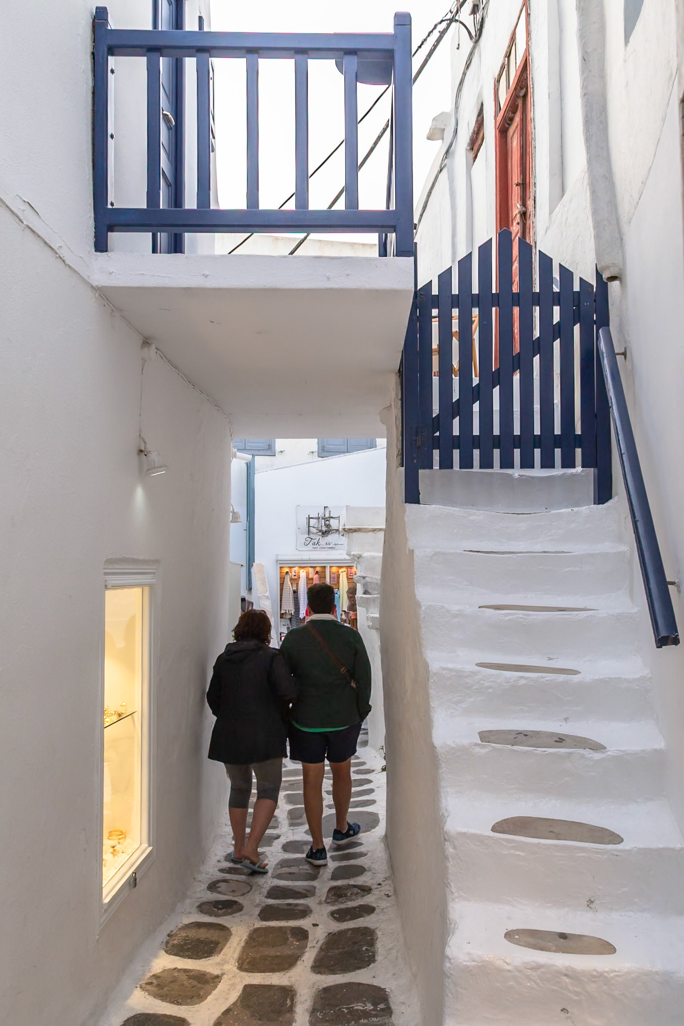 Mykonos, Greece - May 23rd 2018: A couple strolls through a narrow, white-washed street, exploring the unique architecture and charm of the island.