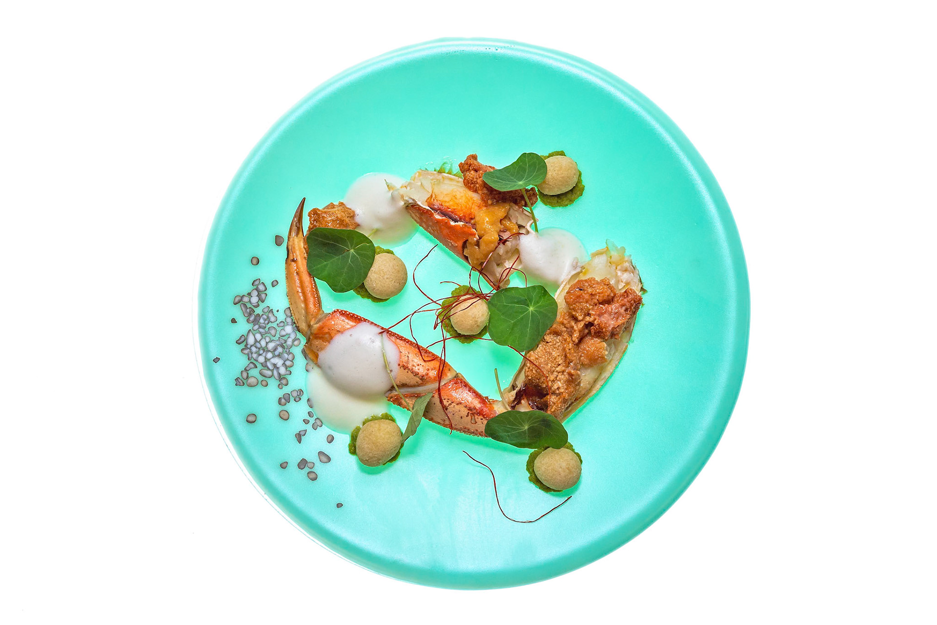 Fog Lark, Portland, Oregon - March 15th 2019: A chef plates a dish with crab, foam, and greens for a diner's culinary experience.