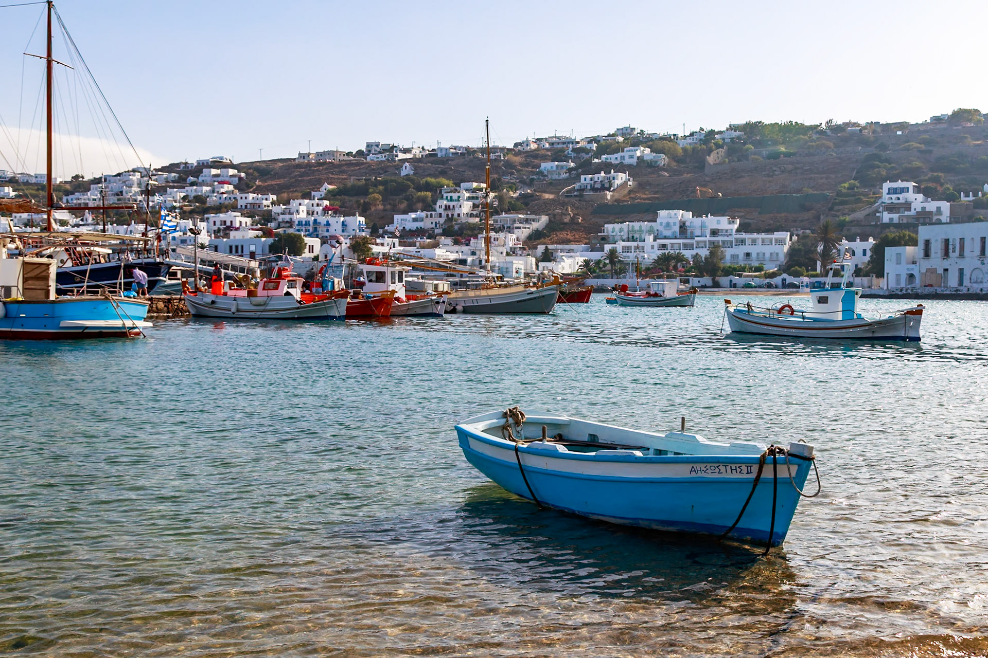 Mykonos, Greece - May 23rd 2018: Fishing boats are moored in the harbor, bobbing gently in the clear water, ready for the next catch.