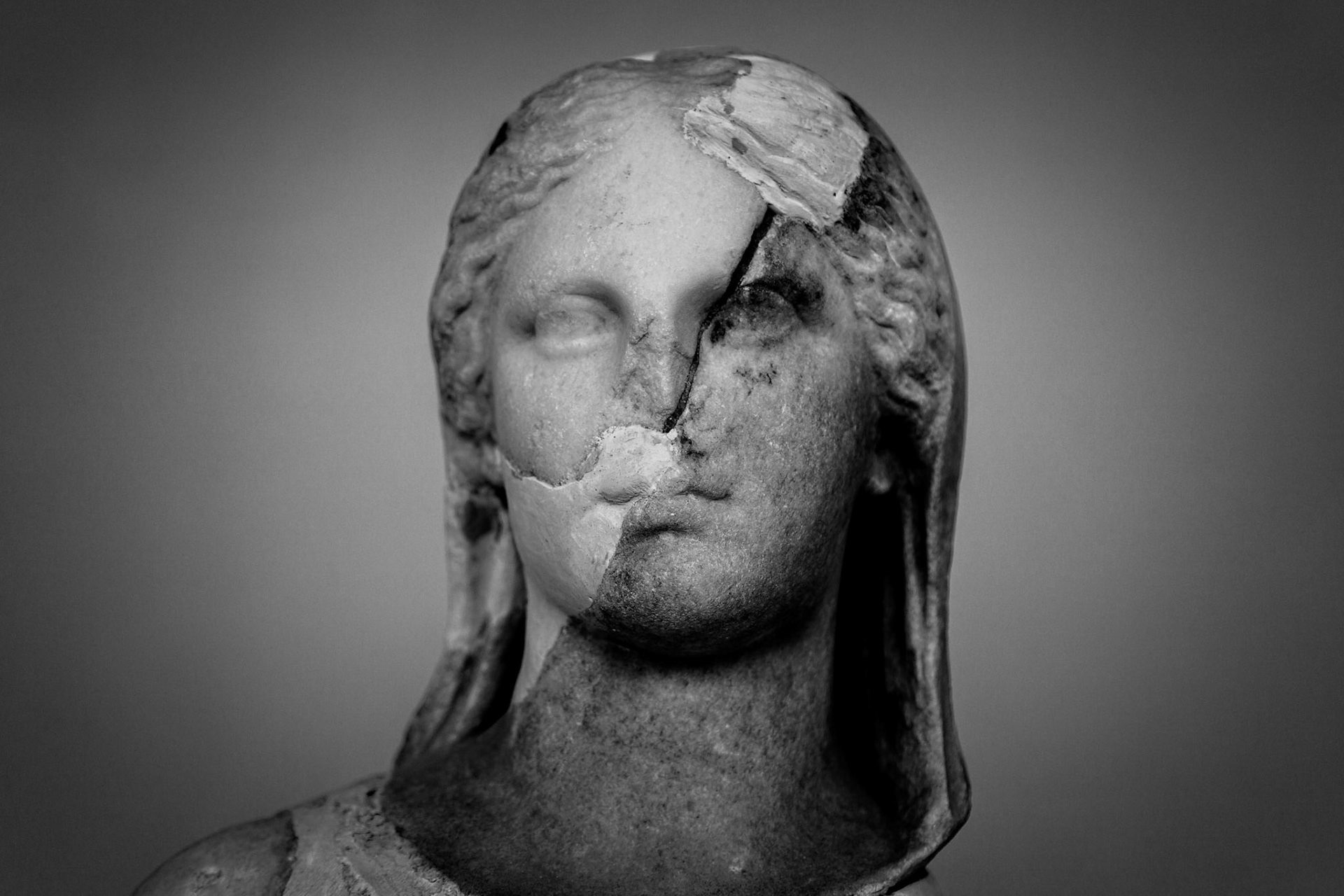 Delos, Greece - May 22nd 2018: A weathered marble bust of a woman stands as a testament to time, its cracked surface a reminder of the island's rich history.