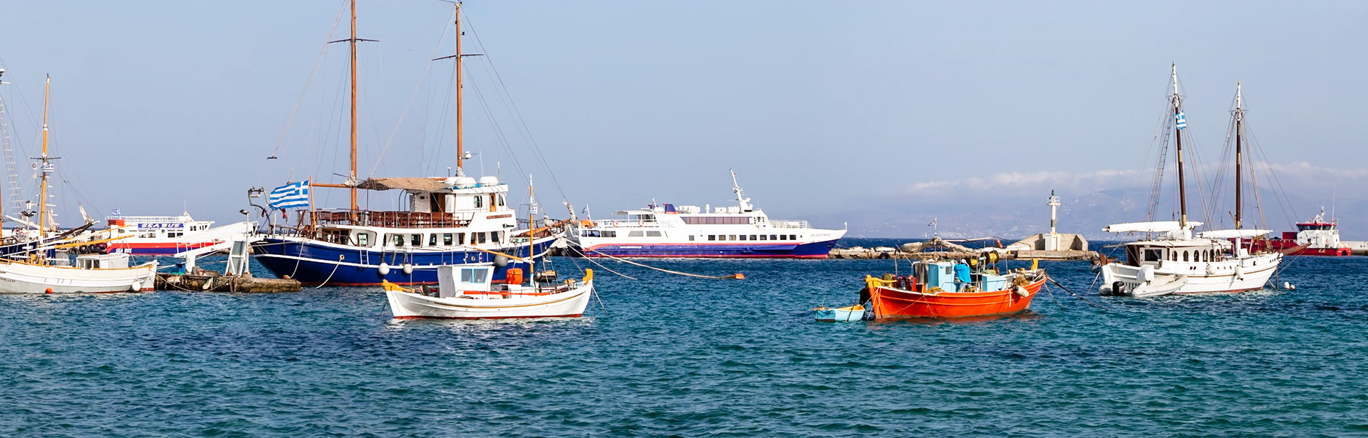 Mykonos, Greece - May 23rd 2018: Boats bob in the harbor, their colorful hulls reflecting in the turquoise water, awaiting passengers and new adventures.