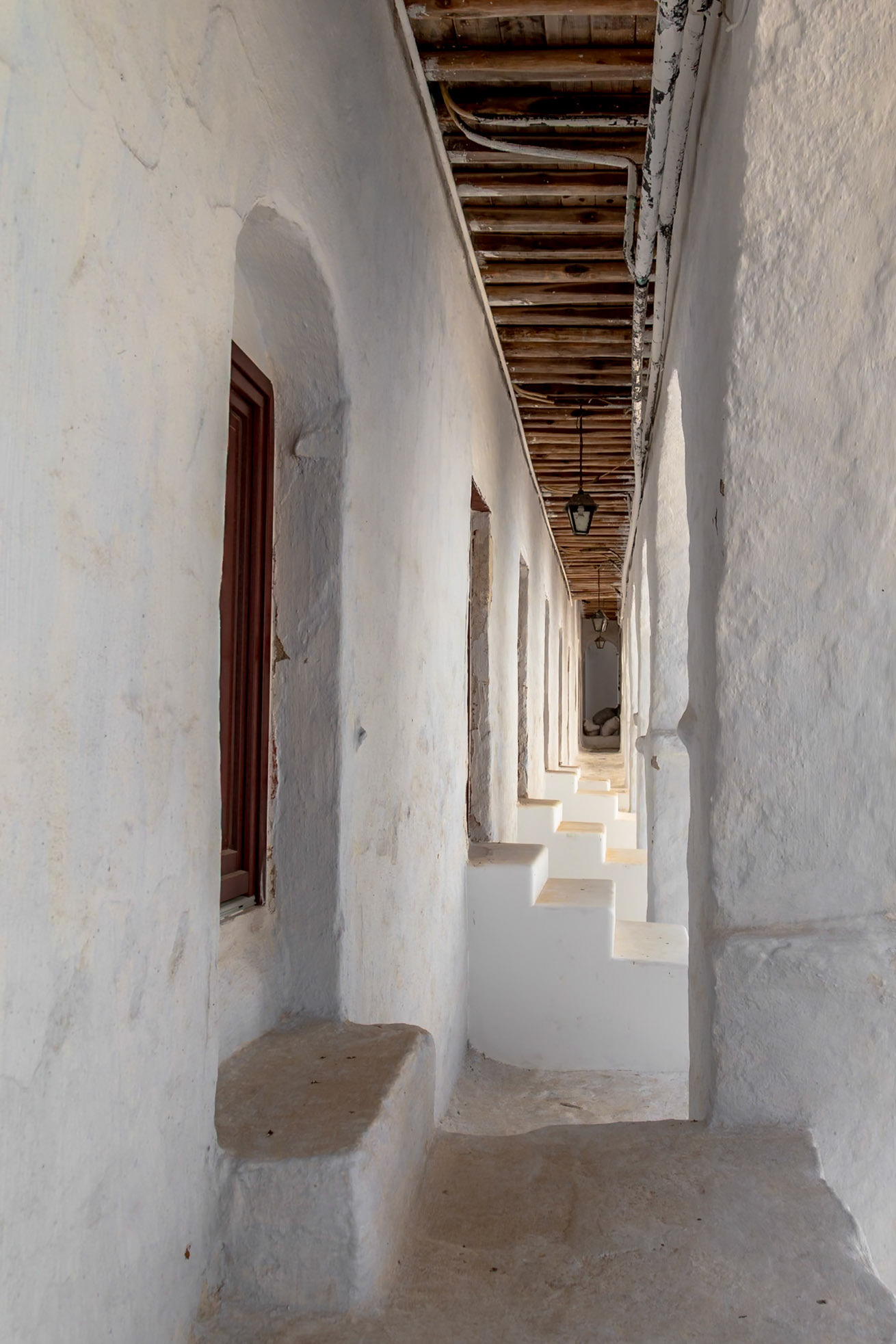 Mykonos, Greece - May 22nd 2018: A whitewashed alleyway with stairs and hanging lamps creates a classic Cycladic scene.