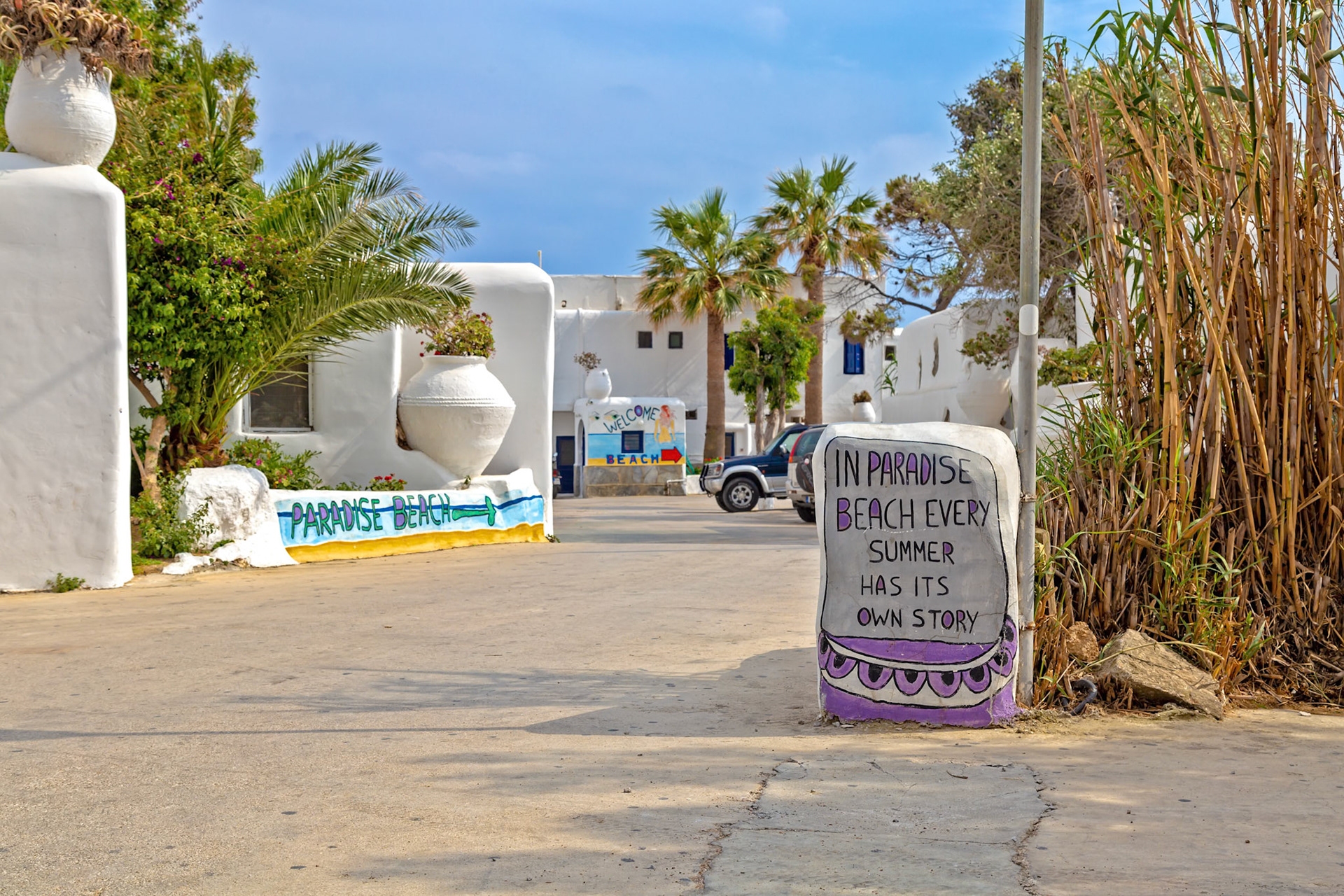 Paradise Beach, Mykonos, Greece - May 24th 2018: A painted sign welcomes visitors with a summer quote, setting the scene for beachgoers.
