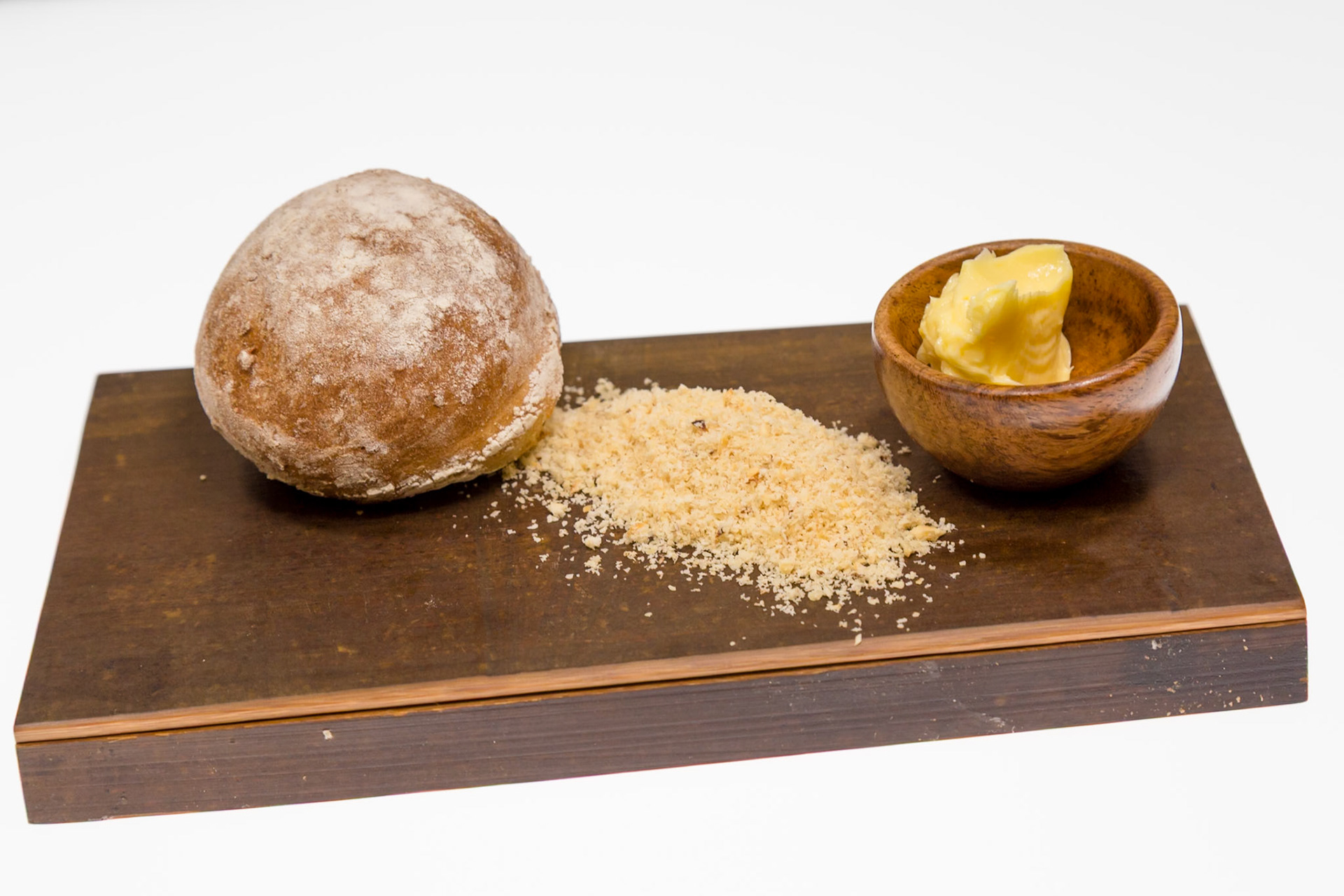 Fog Lark, Portland, Oregon - April 6th 2018: A bread roll, bread crumbs, and butter are presented on a wooden board for a meal.