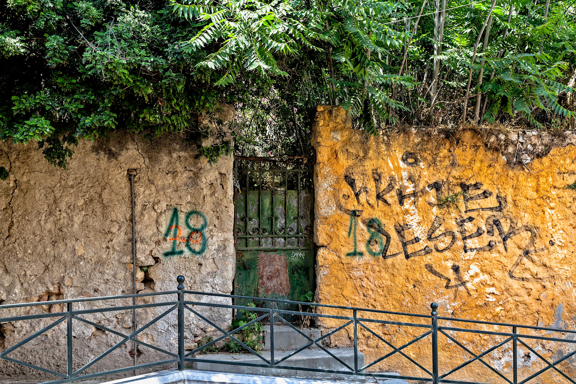 Athens, Greece - May 23rd 2018: A weathered wall with graffiti and a rusty gate, possibly marking an abandoned or forgotten space in the city.