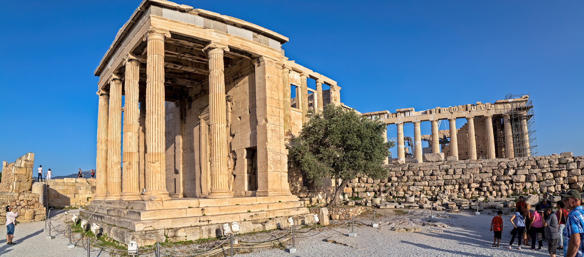 Acropolis, Athens, Greece - May 23rd 2018: Tourists visit the Erechtheion and Parthenon, ancient temples, to learn about Greek history and culture.
