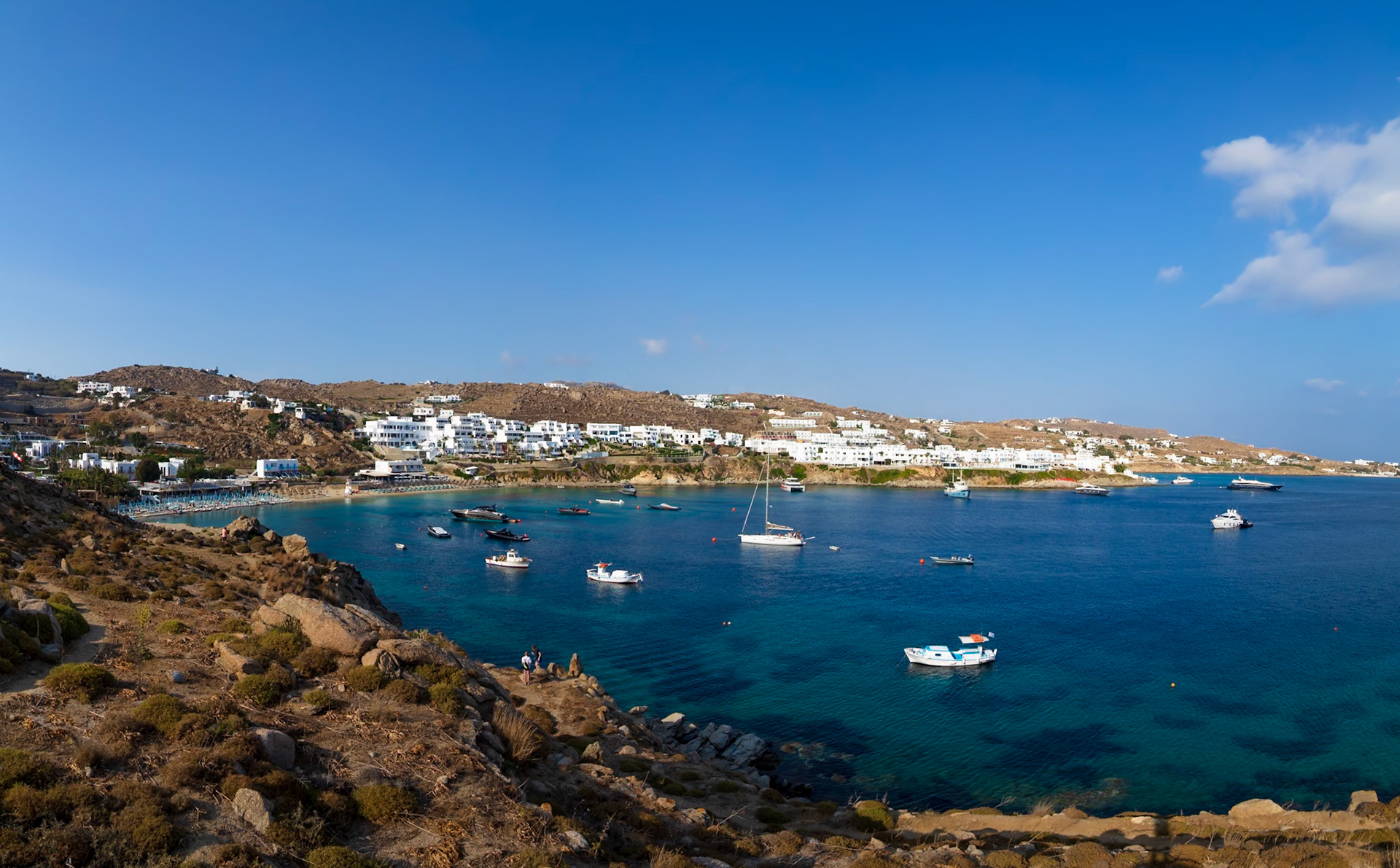 Psarou Beach, Mykonos, Greece - May 24th 2018: Boats dot the bay as tourists enjoy the beach and clear waters of Mykonos.