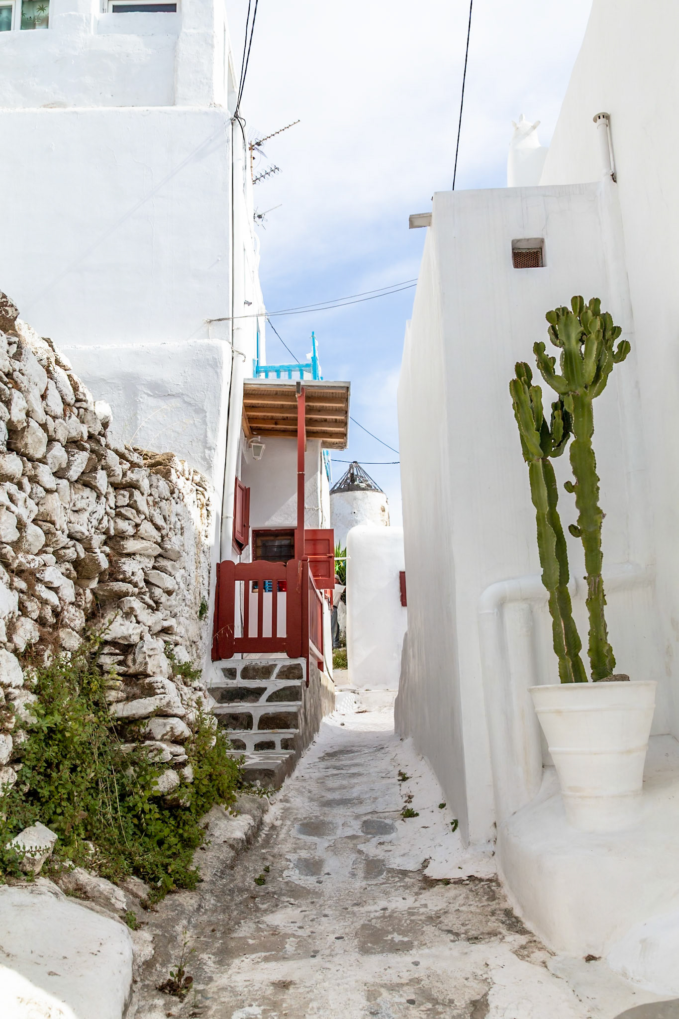 Mykonos, Greece - May 22nd 2018: A narrow, winding alleyway between white buildings, showcasing the island's unique architecture and charm.