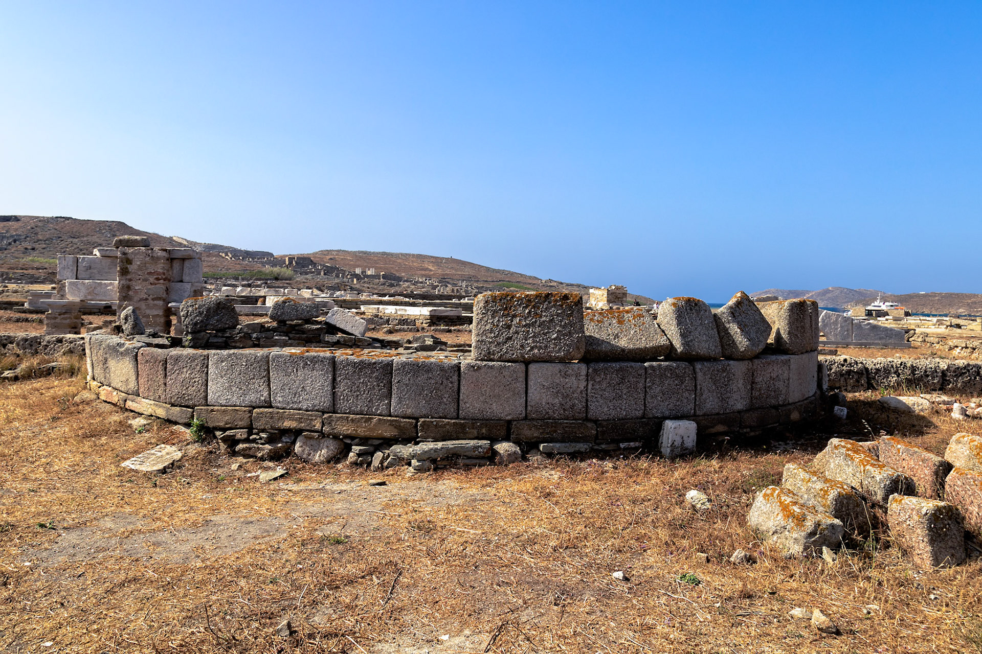 Delos, Greece - May 22nd 2018: Ruins of an ancient structure stand against a clear blue sky. The site is a reminder of Delos's rich history and cultural significance.