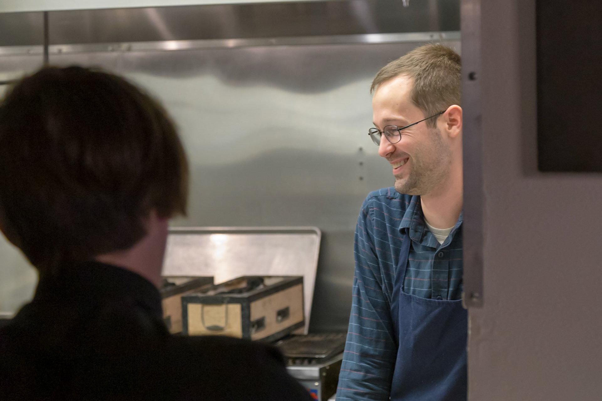 Fog Lark, Portland, Oregon - April 6th 2018: A smiling chef in an apron chats with a coworker in a professional kitchen setting.