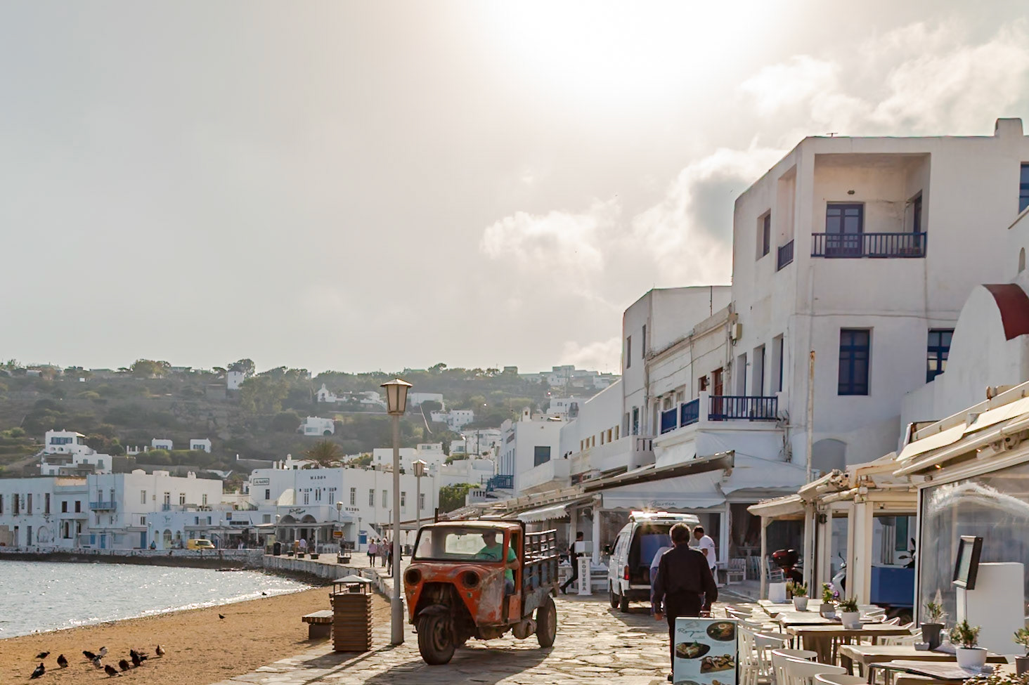 Mykonos, Greece - May 23rd 2018: A driver in a small truck navigates the narrow streets, delivering goods to local businesses.