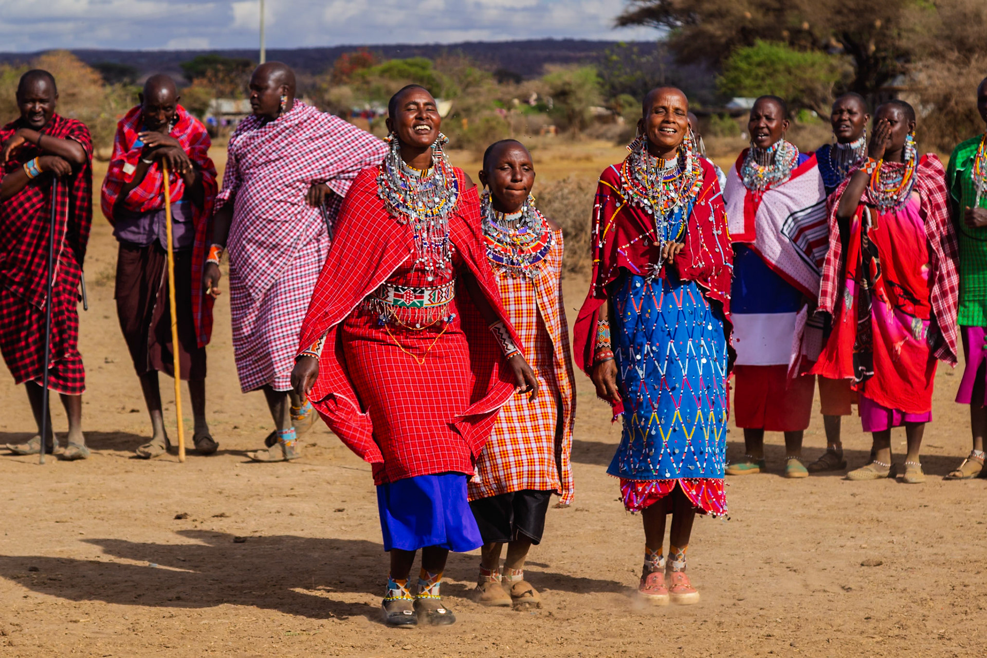 Maasai women and children in Kenya, adorned in traditional attire, participate in a cultural celebration in their village.