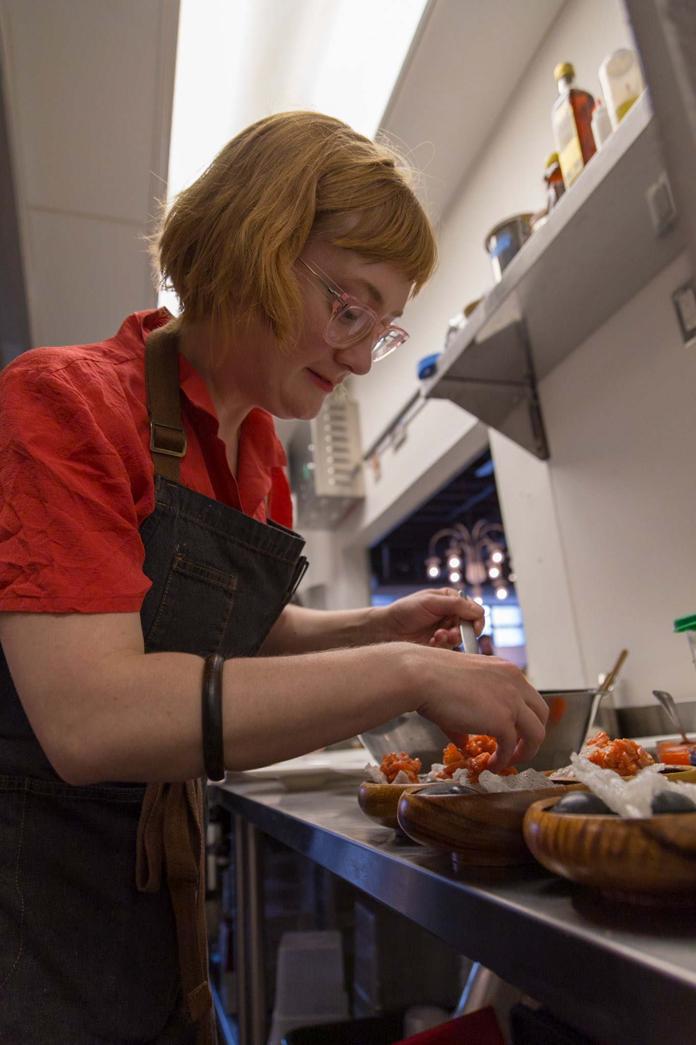 Fog Lark, Portland, Oregon - April 6th 2018: A chef plates a dish with salmon in a restaurant kitchen, preparing it for service.