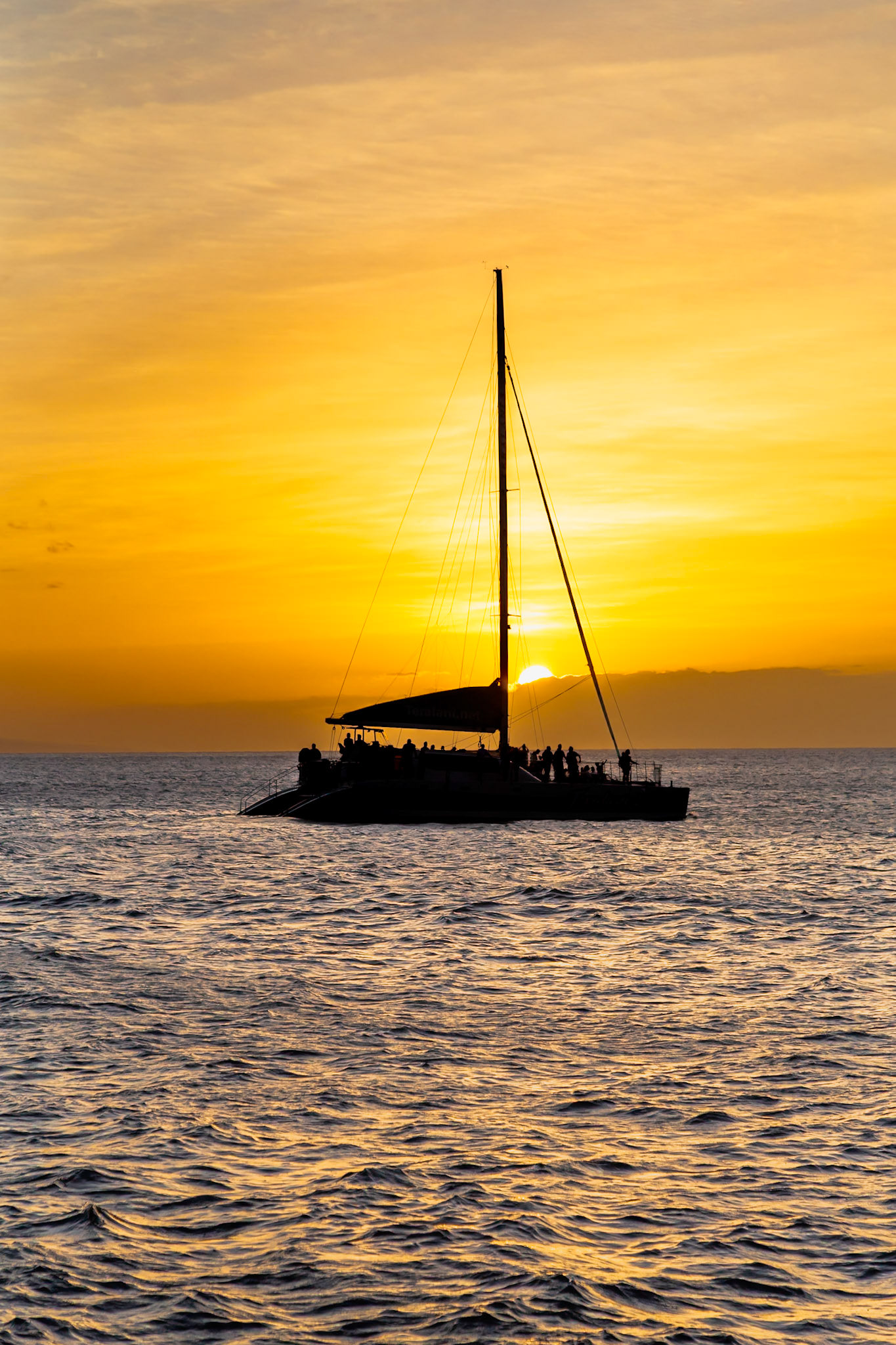 Maui, Hawaii, USA - April 7th 2022: Silhouetted passengers enjoy a sunset cruise on a catamaran, creating a serene and picturesque scene.