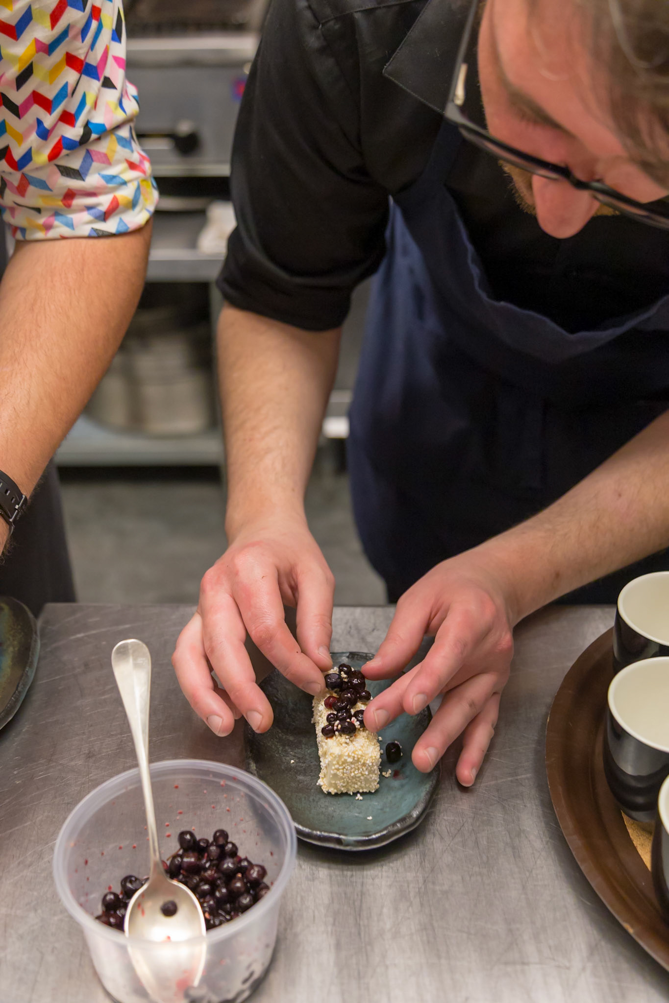 Fog Lark, Portland, Oregon - April 6th 2018: A chef carefully plates a dish, adding berries to a sesame-covered item for a visually appealing dessert.