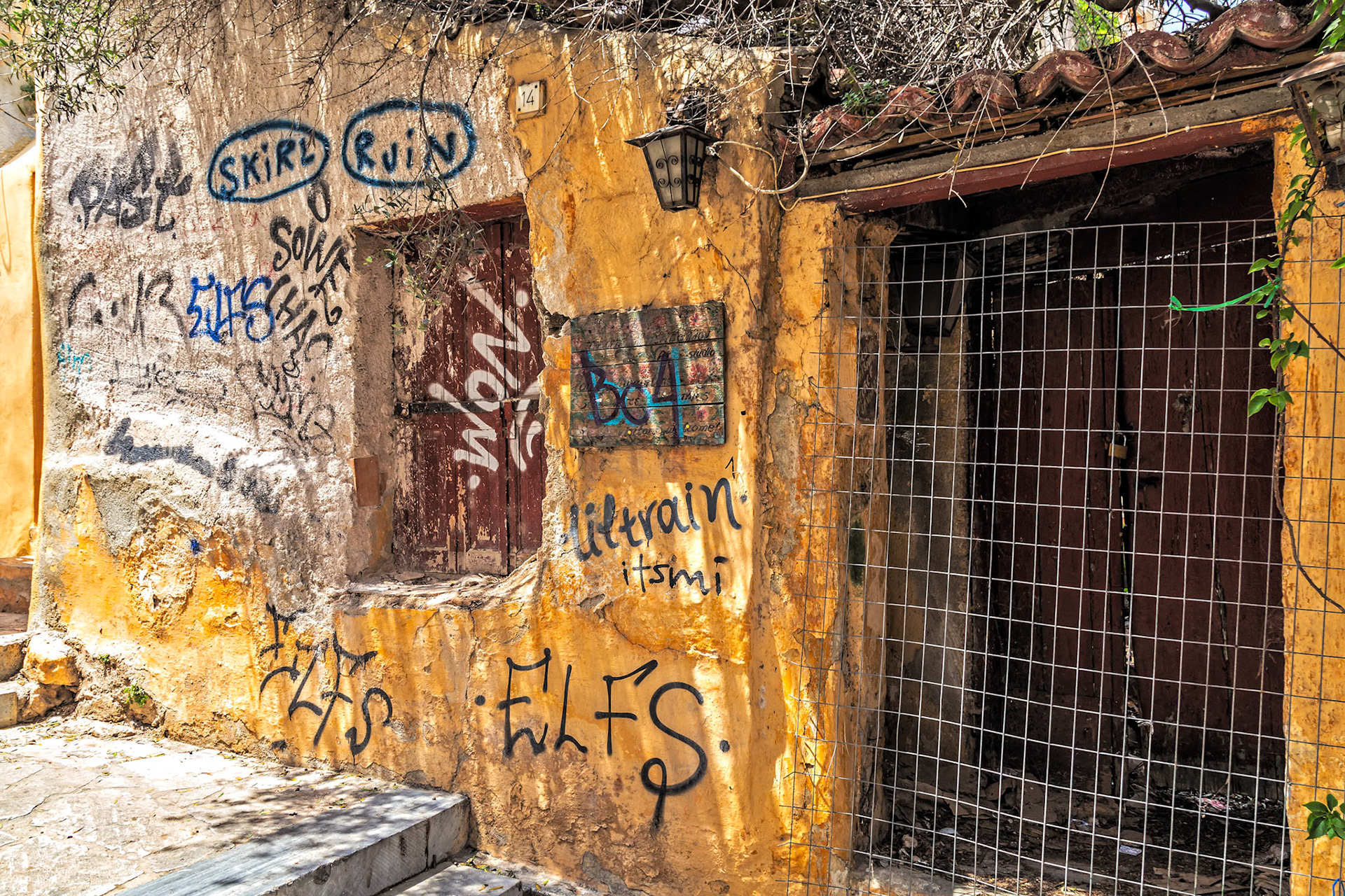 Athens, Greece - May 23rd 2018: An old building with graffiti on the walls and doors, showing the effects of time and urban art.