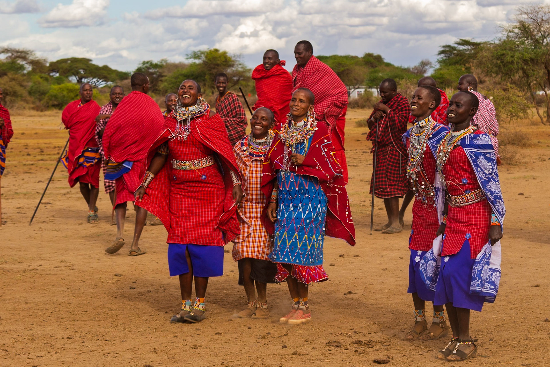 Maasai people in Kenya are celebrating in their village, wearing traditional clothing and jewelry.