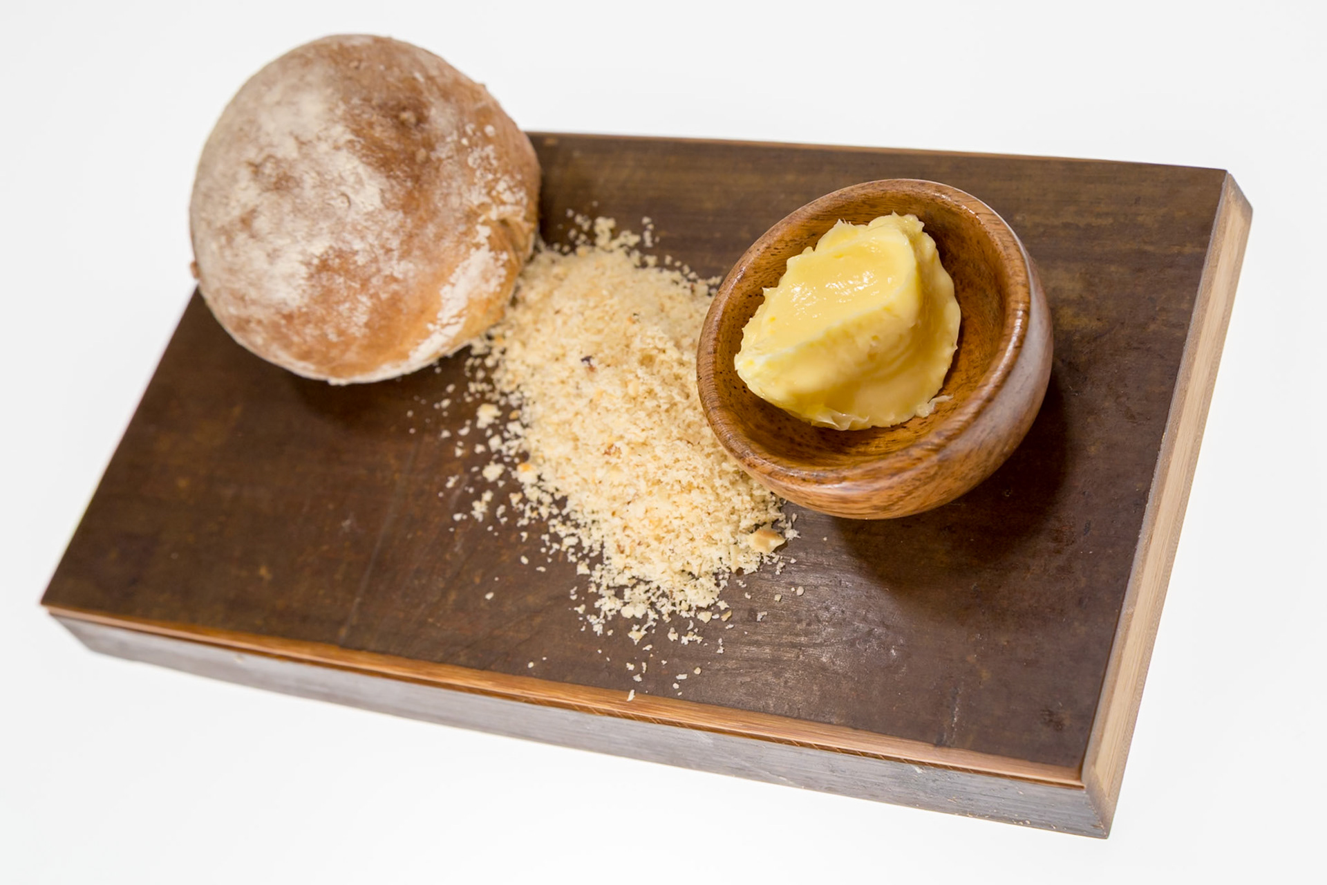 Fog Lark, Portland, Oregon - April 6th 2018: A bread roll, bread crumbs, and butter are presented on a wooden board for a meal.
