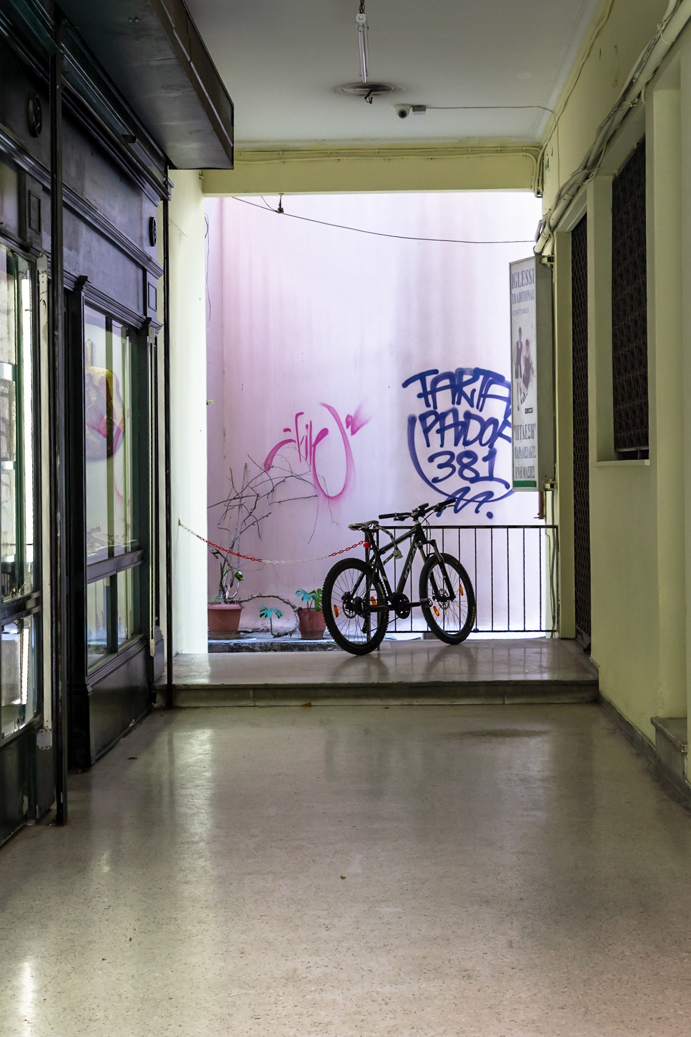 Athens, Greece - May 23rd 2018: Two bicycles are parked in a hallway in front of a wall with graffiti, possibly for storage or a quick stop.