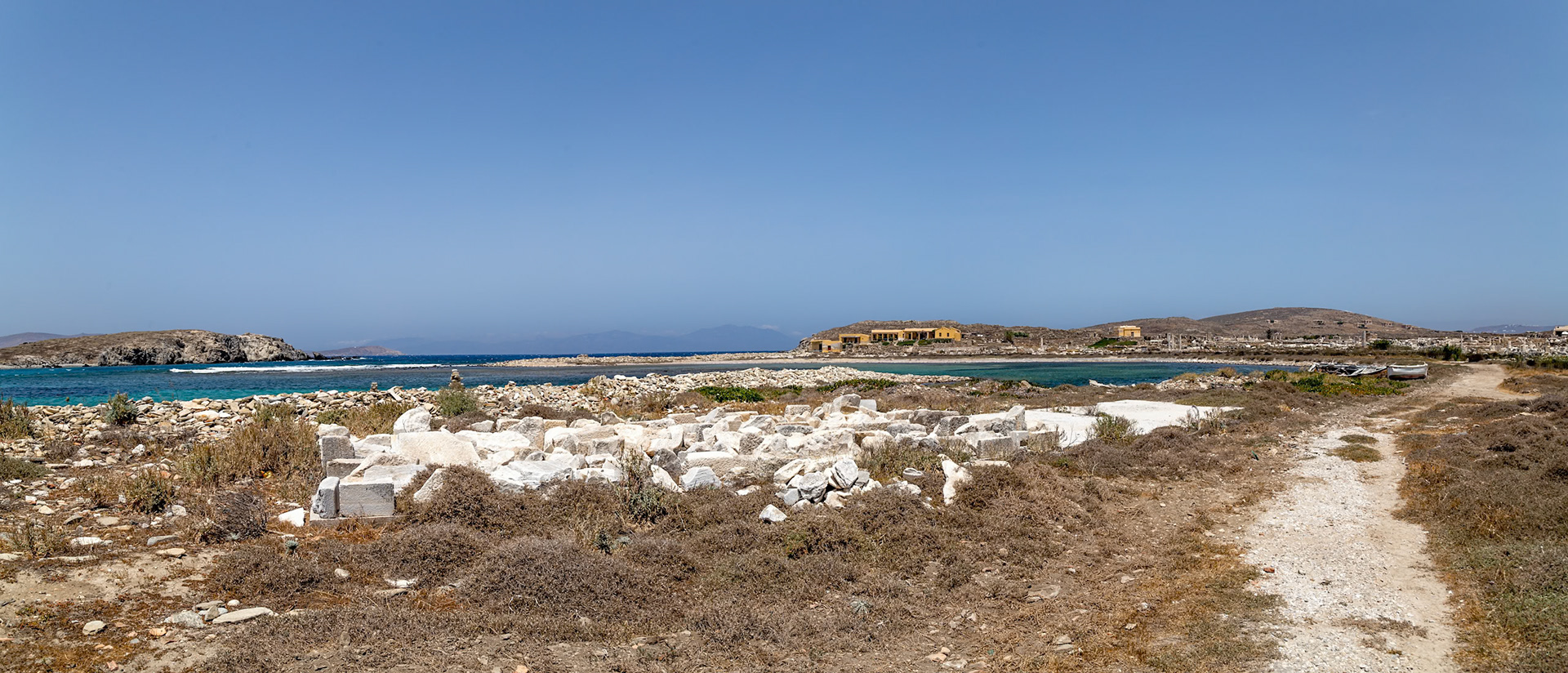Delos, Greece - May 22nd 2018: Ruins of ancient structures sit on the island of Delos, a UNESCO World Heritage site, attracting tourists to explore its rich history.