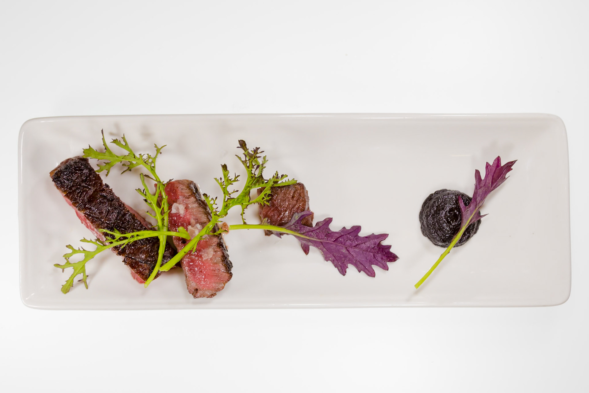 Fog Lark, Portland, Oregon - April 6th 2018: A chef plates a steak dish with greens and a dark sauce, showcasing culinary artistry.