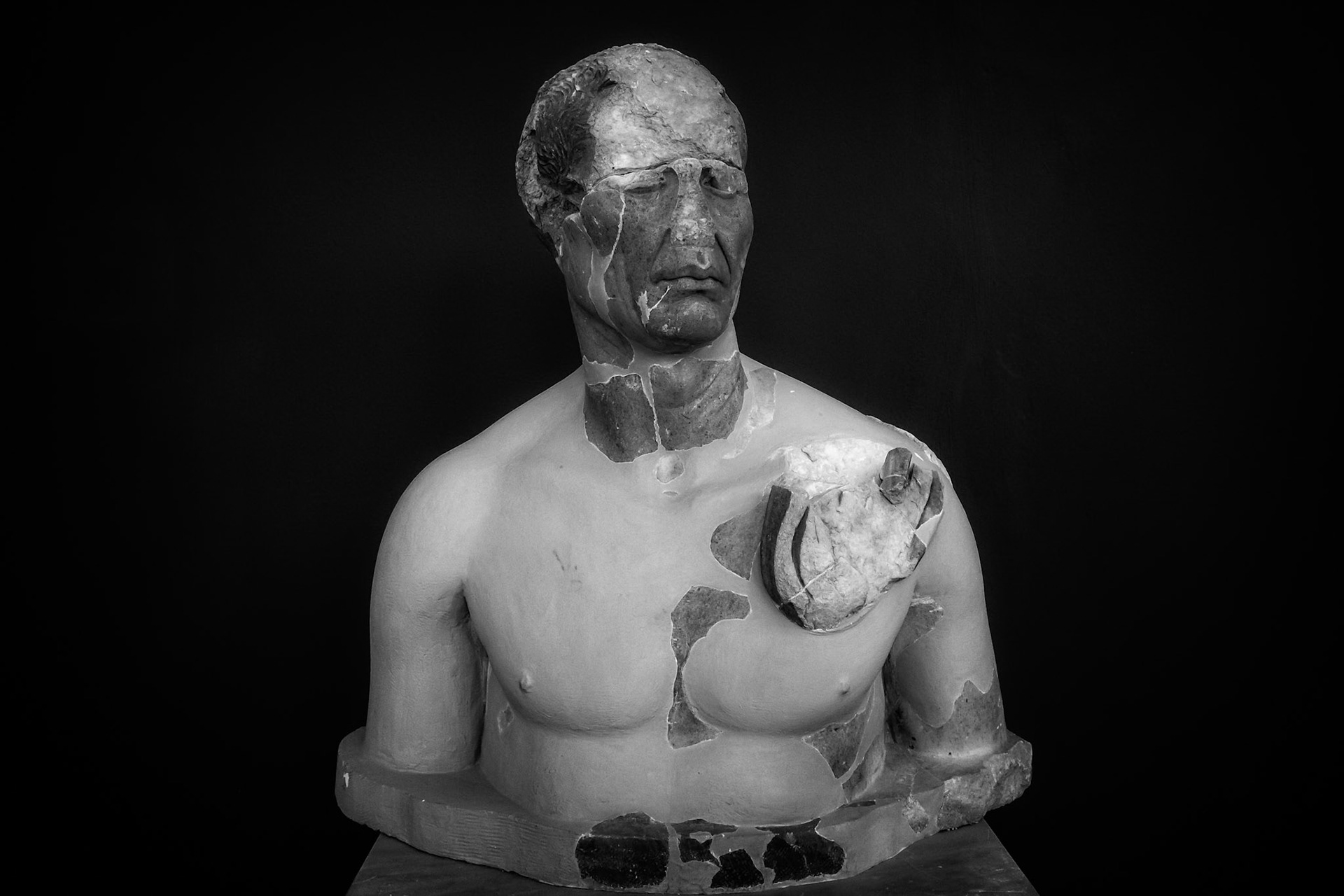 Delos, Greece - May 22nd 2018: A bust of a man, likely a historical figure, is displayed. The statue is damaged, with missing pieces, revealing the stone underneath.