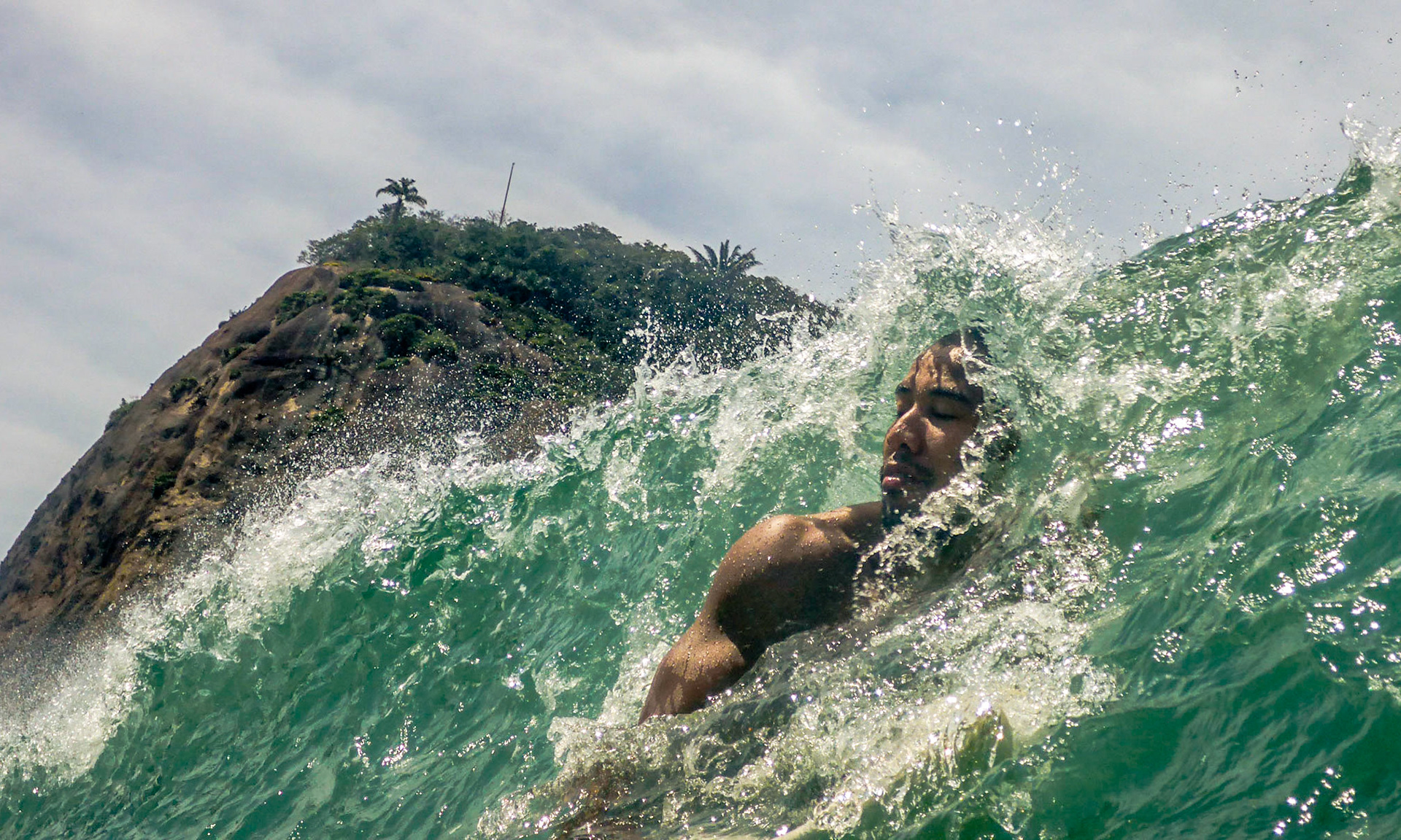 A surfer passes under a wave while waiting for another to catch off the shore near Leme Rock at the end of Copacabana Beach in Rio de Janeiro, Sept. 17, 2015.