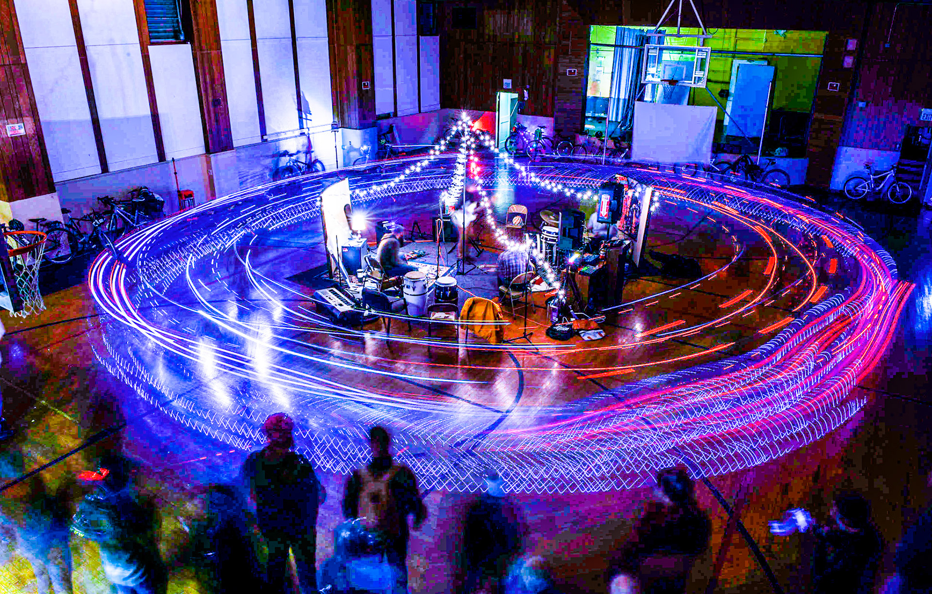 Light trails from participants Bike Party outing ride circles swirl around a band playing in the middle of a gym in an abandoned Catholic school in Haughville on the West side of Indianapolis, Jan. 8th, 2017.
