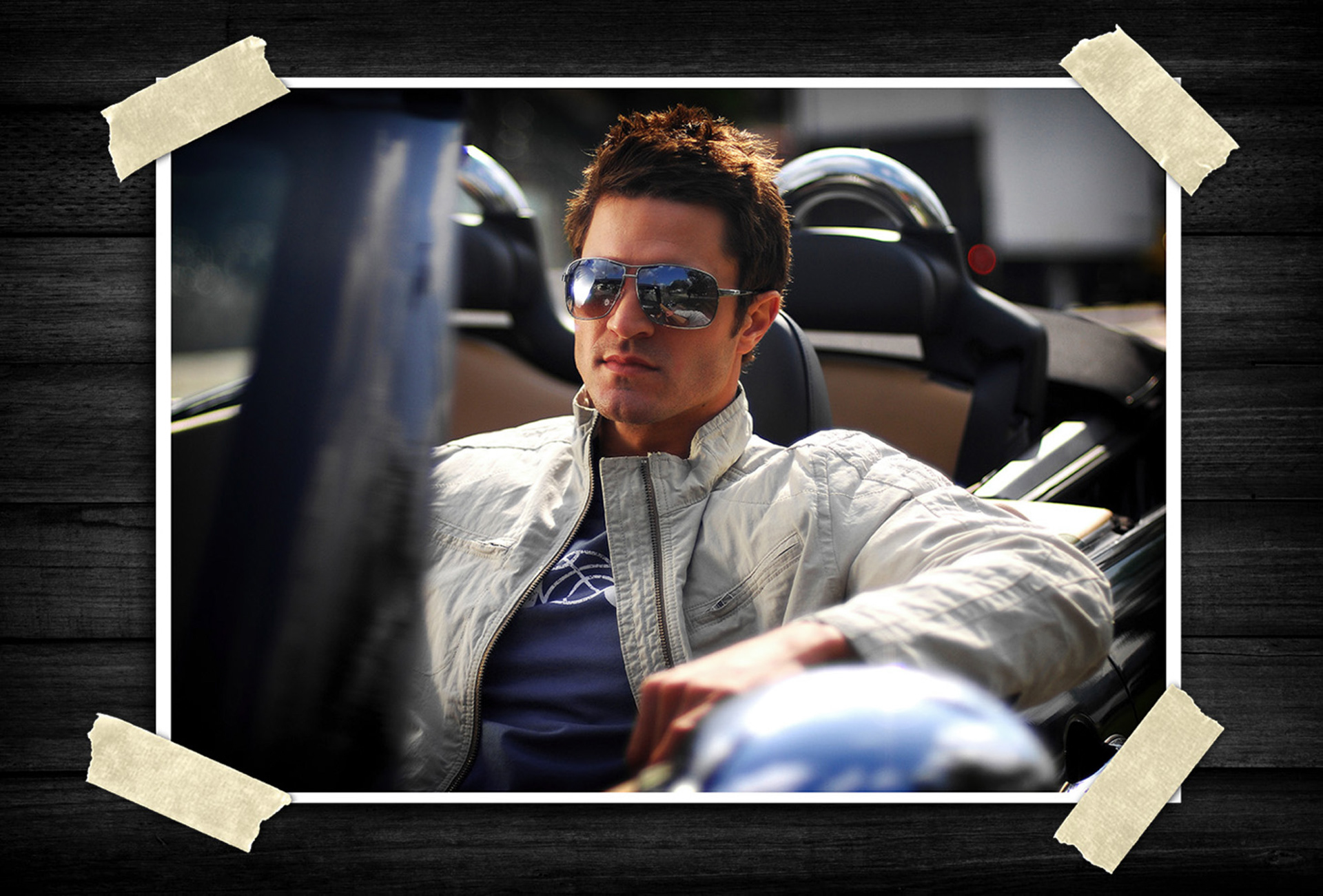 Lifestyle portrait of a man wearing sunglasses and a light jacket while sitting in a convertible sports car, photographed with an upscale urban feel.