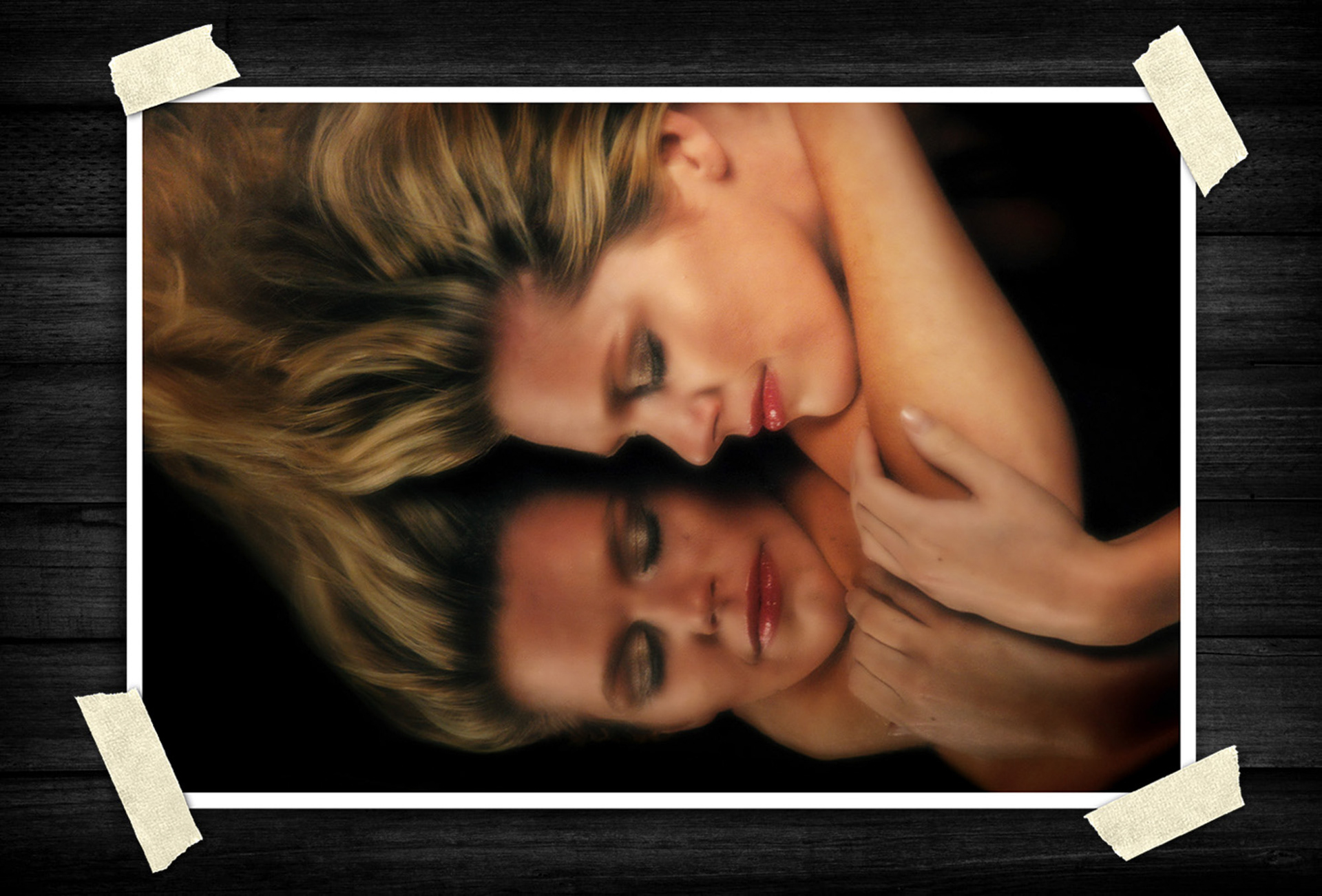 Artistic beauty portrait of a blonde woman resting against a reflective surface, creating a mirrored effect with soft lighting and glamorous styling.