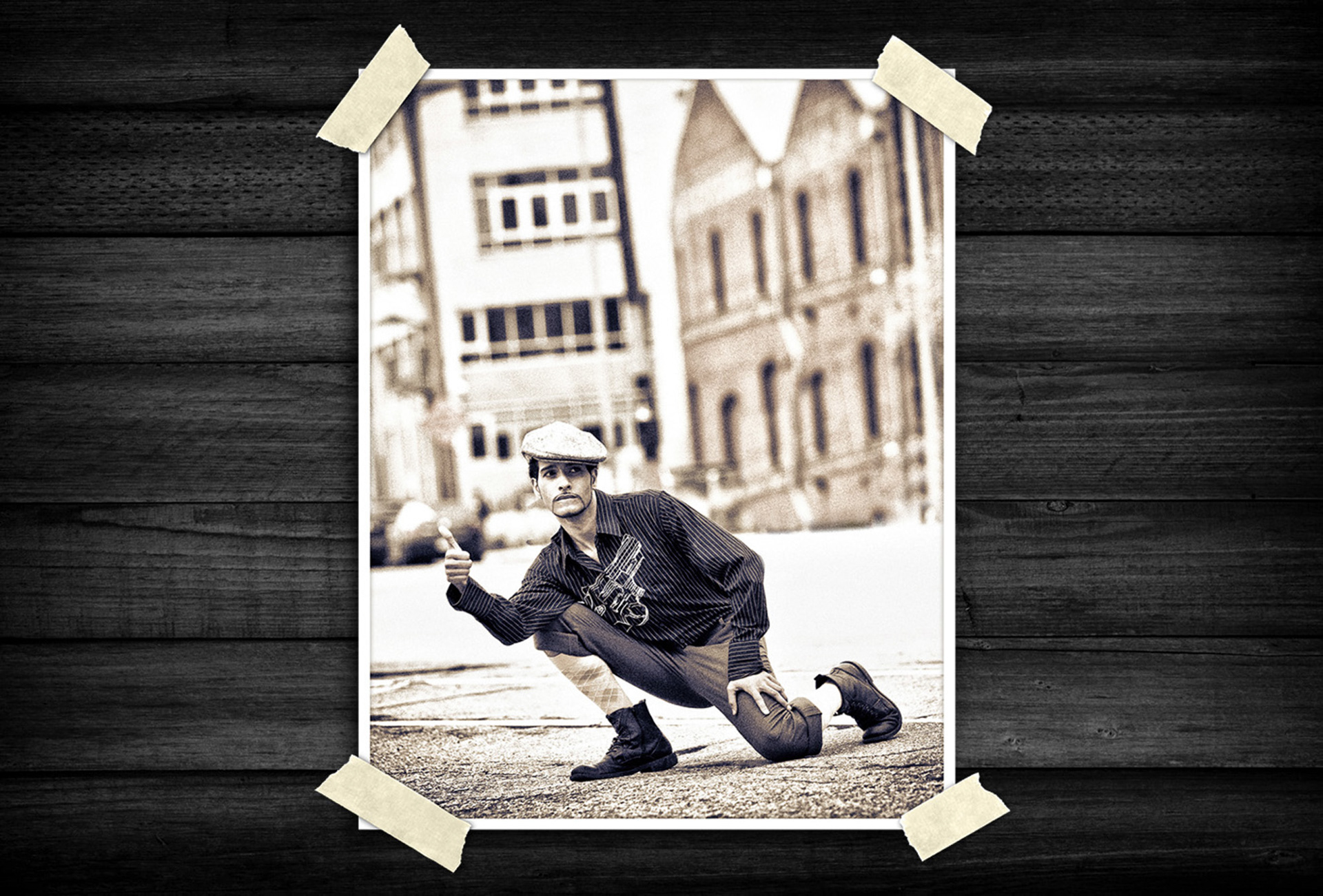 Sepia-toned portrait of a person in vintage-inspired clothing and cap, posing dramatically on a city street with an urban background.