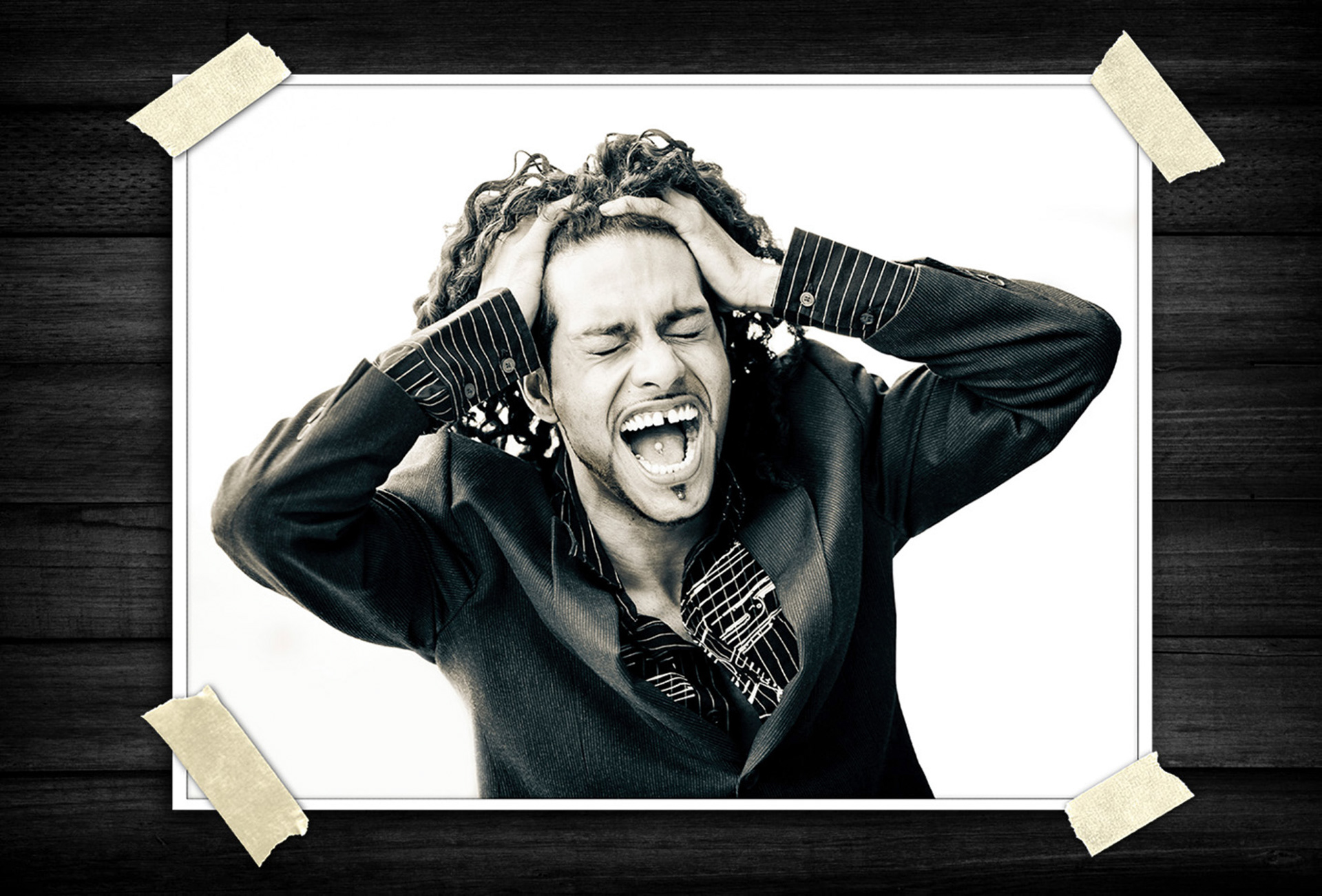 Black-and-white expressive portrait of a person with curly hair gripping their head and shouting, conveying intense emotion and dramatic energy.