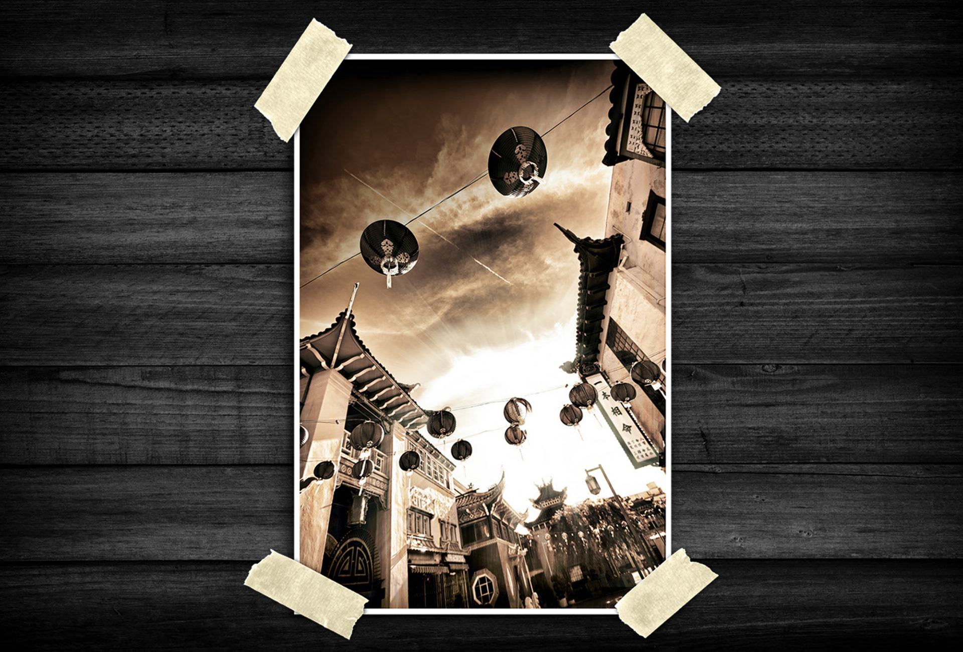 A dramatic low-angle view captures a traditional street lined with ornate buildings and curved rooflines. Hanging lanterns stretch across the scene in layered rows, drawing the eye upward toward textured clouds and streaked skies. Bright sunlight bursts through the center, creating strong highlights and silhouettes, while the sepia tones give the image a nostalgic, cinematic atmosphere.