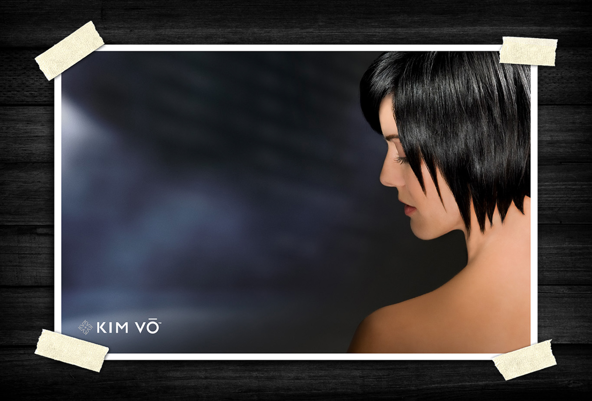 Side-profile beauty portrait of a person with a sleek short black hairstyle, softly lit against a dark background with a calm and elegant mood.