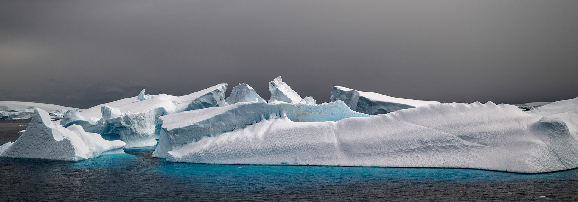 Grey, white, blue and near black. The size and arrangement and contrast of these antartic iceburgs with the grey skies and icy blue reflections seemed magical to me as we cruised by.