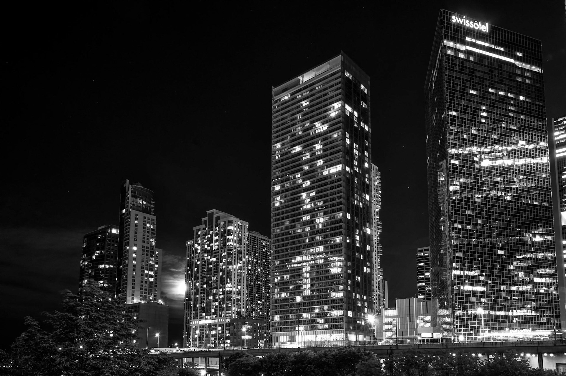 Swissotel on the Chicago river as the full moon tries to peak around a high rise in the background.