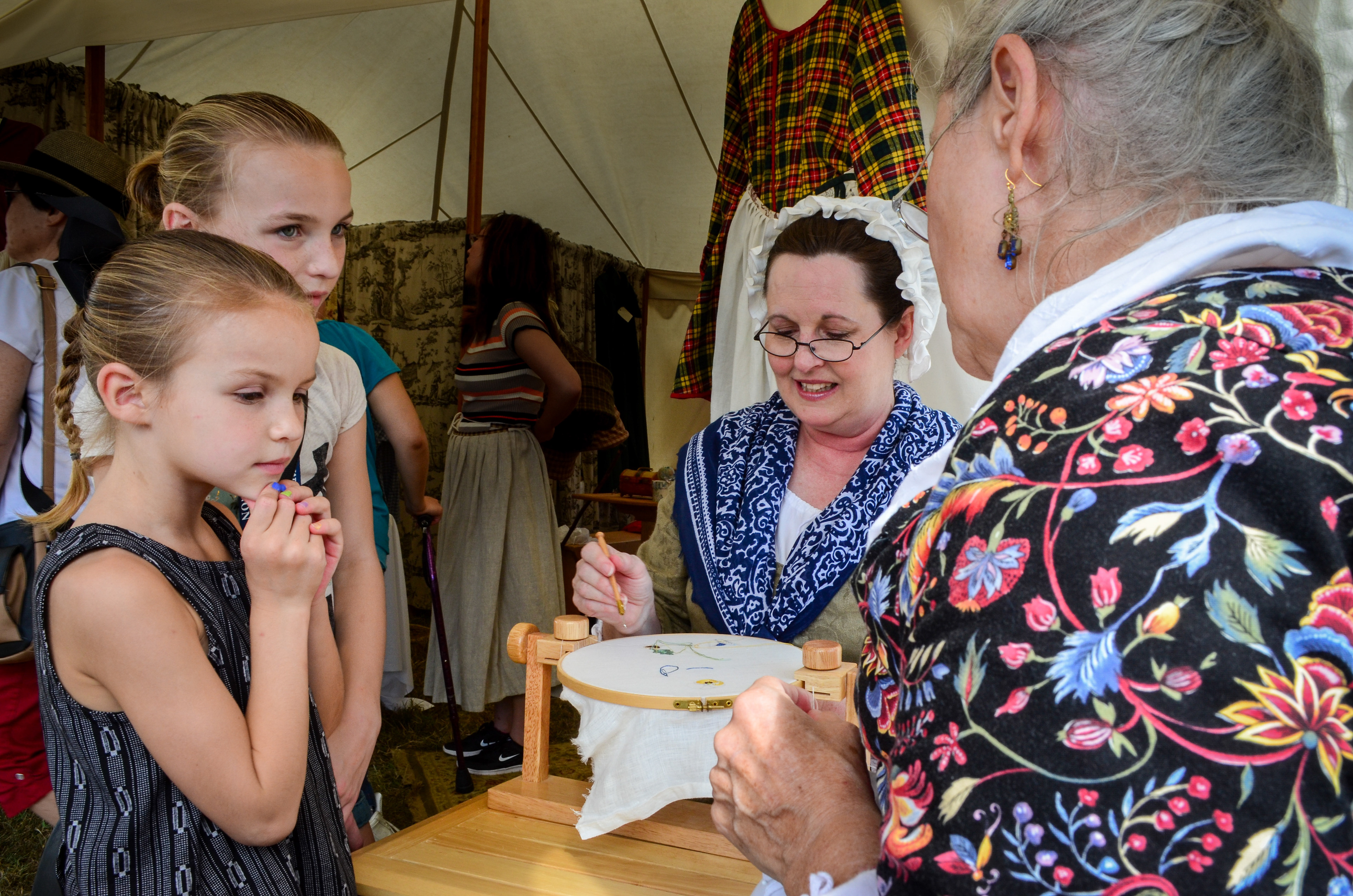 The ladies of Sycamore Spring Clothiers exhibit their hand embroidery skills to engrossed onlookers. George Washington's Mount Vernon Colonial Market & Fair.